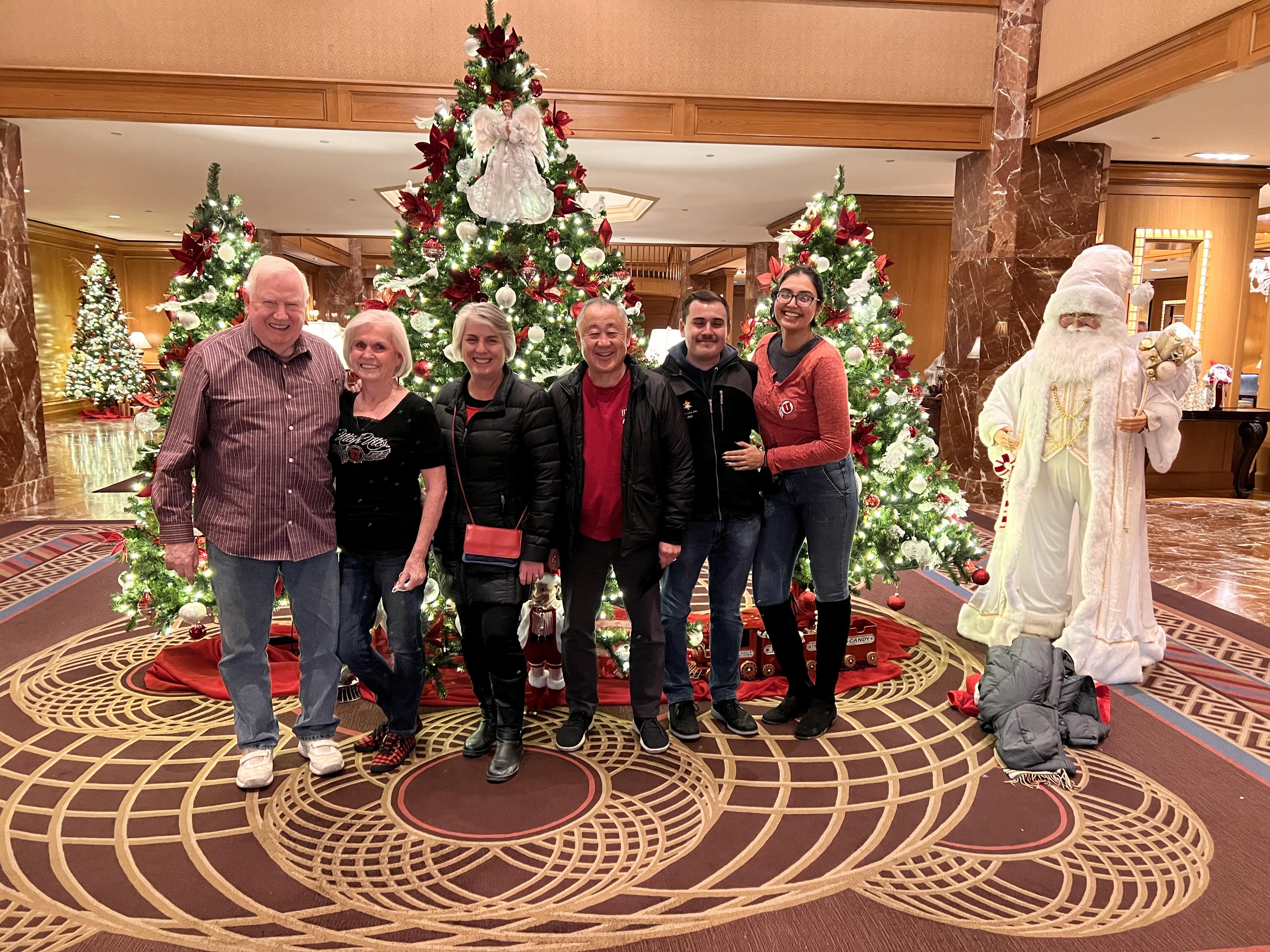 A group of people posing for a photo in front of a christmas tree