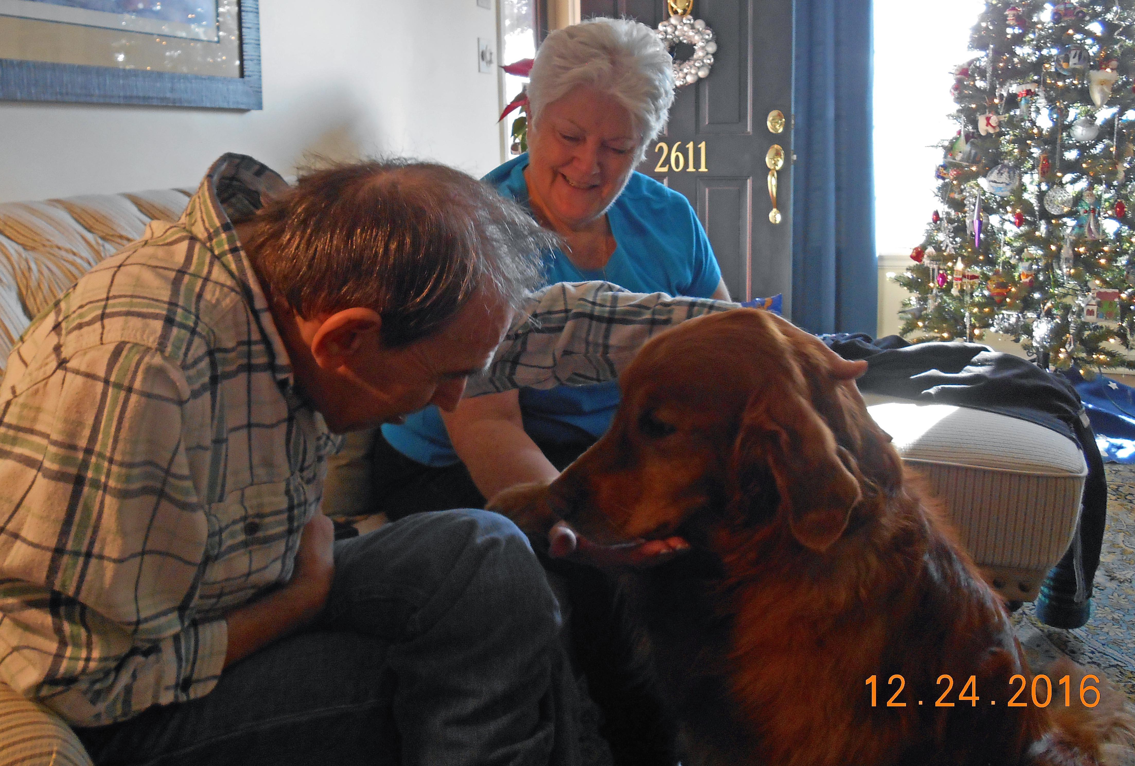A man and woman petting a dog