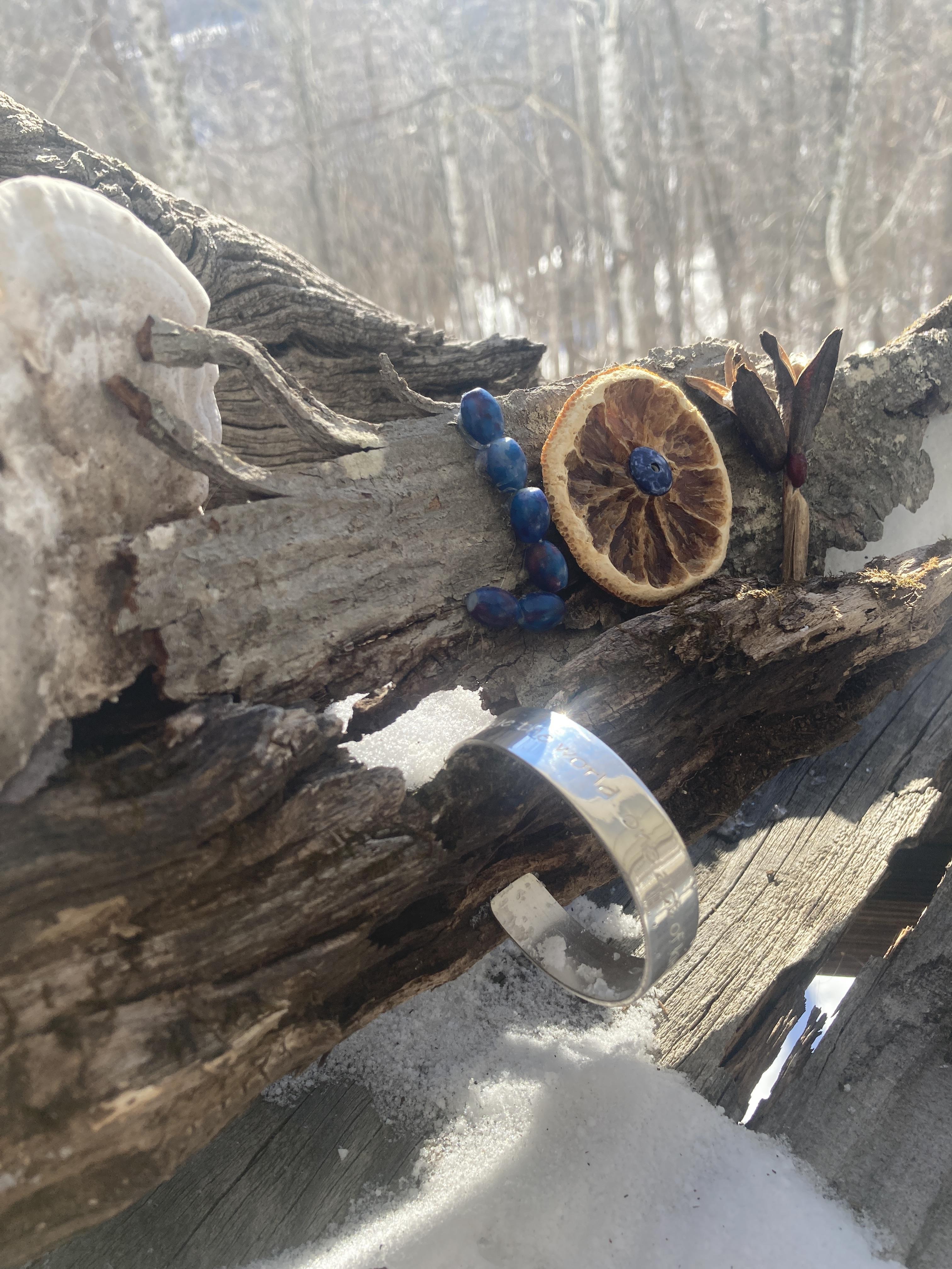 A bracelet and a piece of dried orange on a log