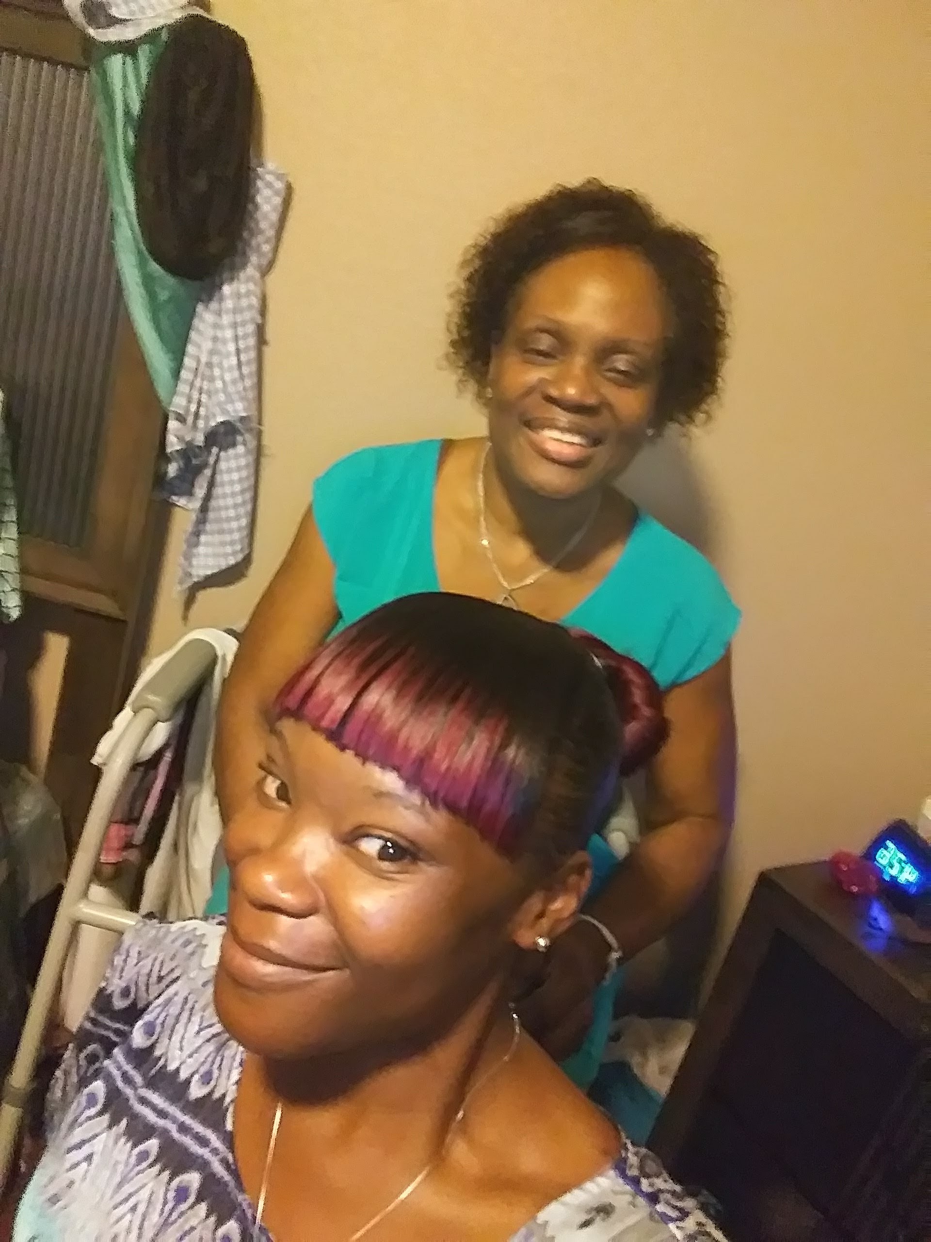 A woman smiling with another woman in her hair