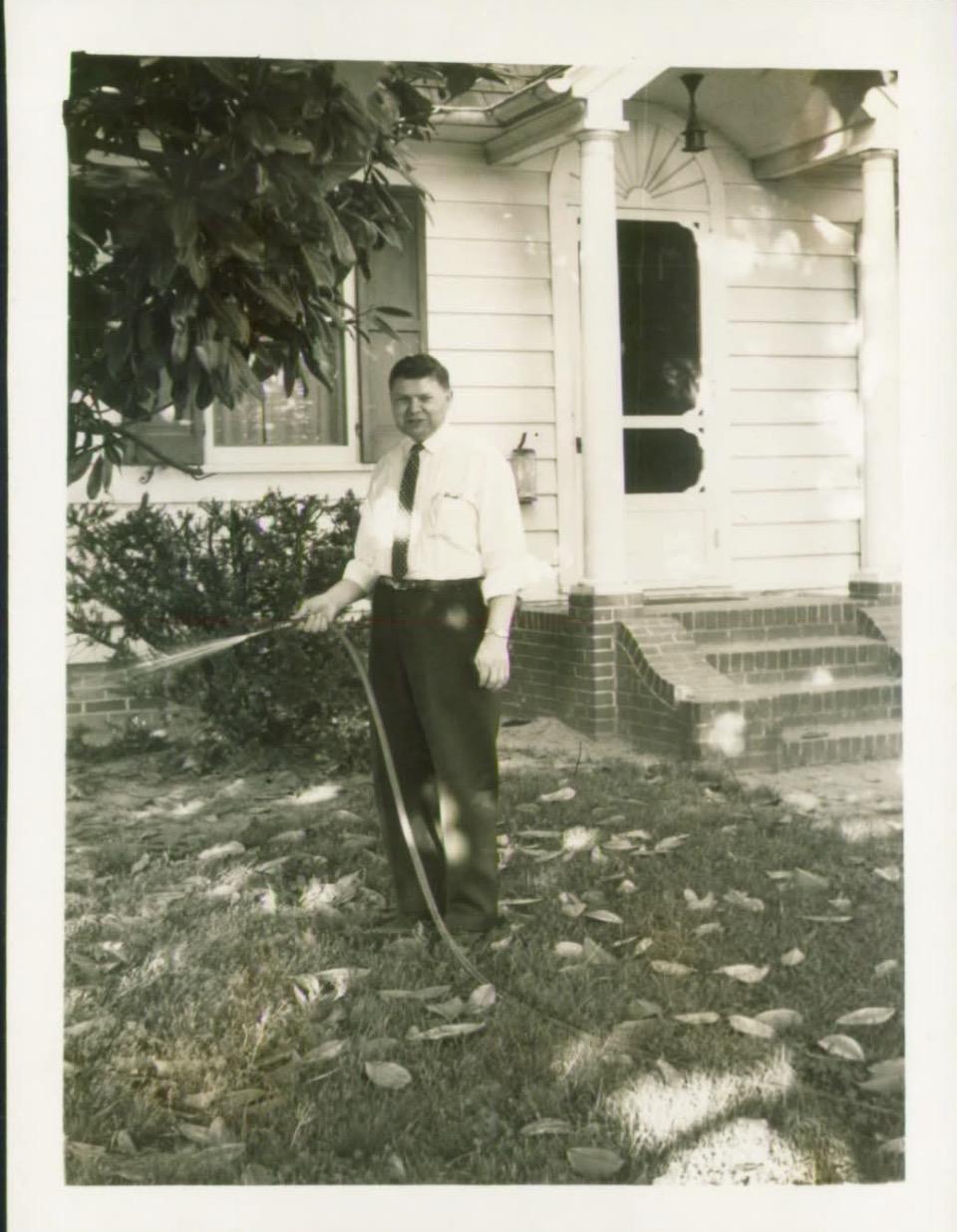 A man holding a rake in front of a house