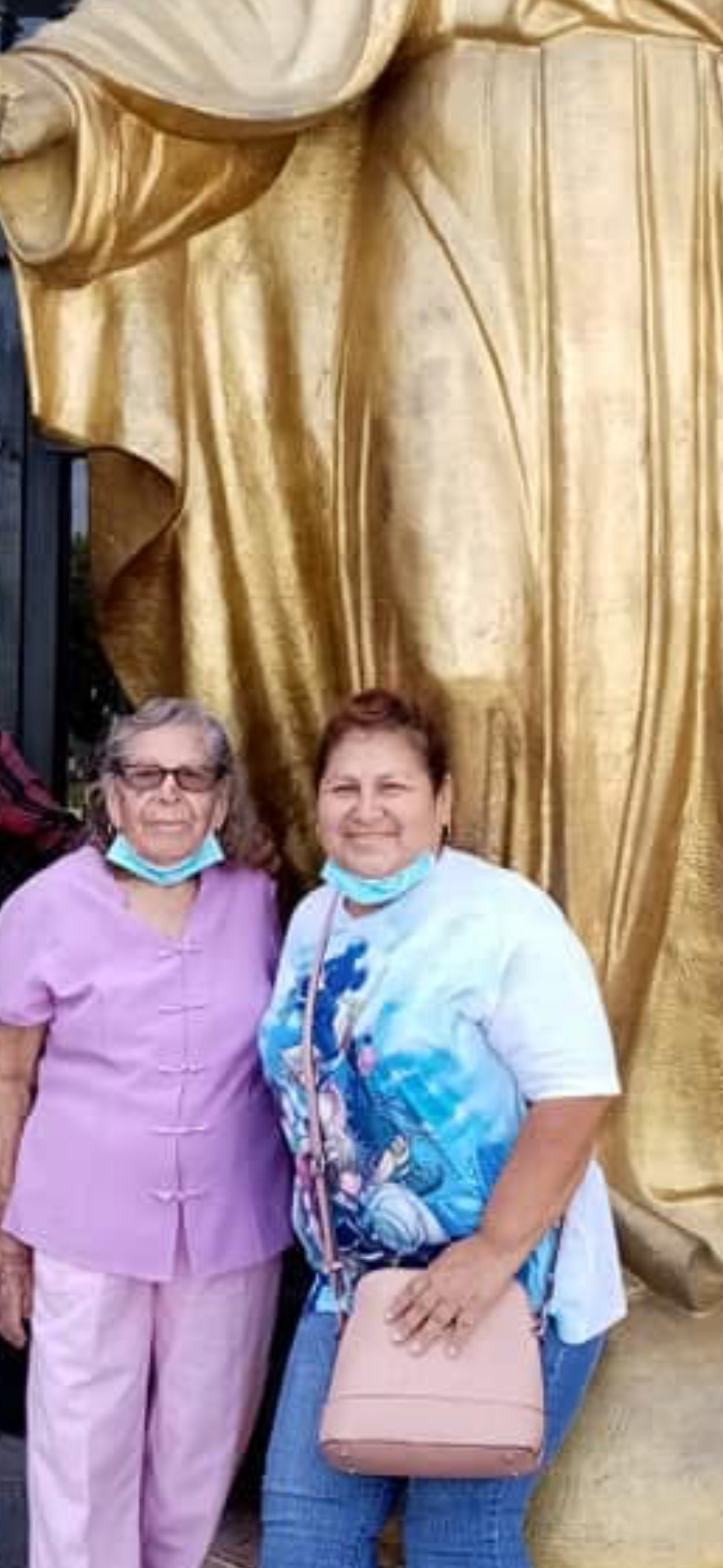 Two women standing in front of a gold curtain