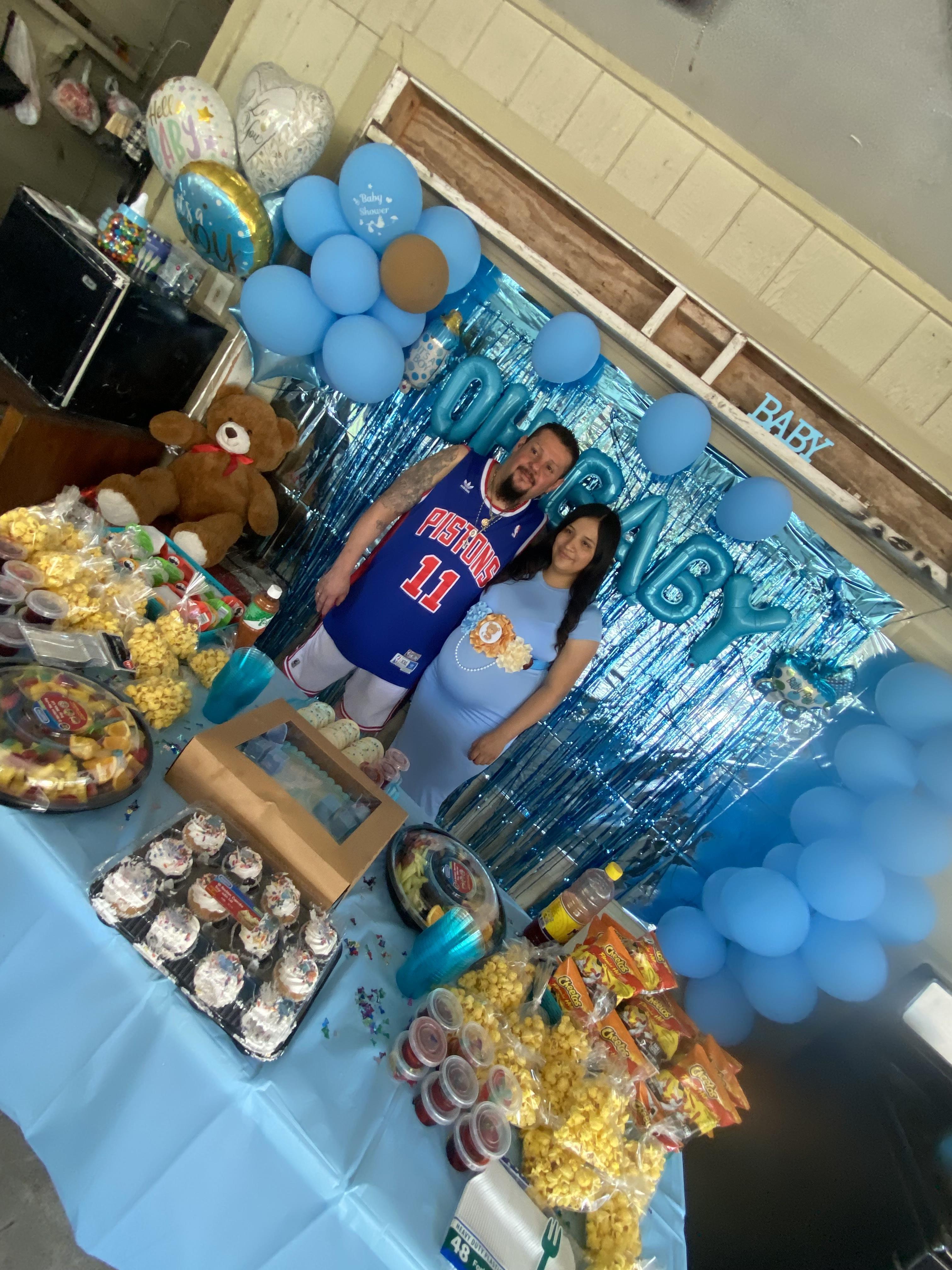 A man and woman standing in front of a table with food and balloons