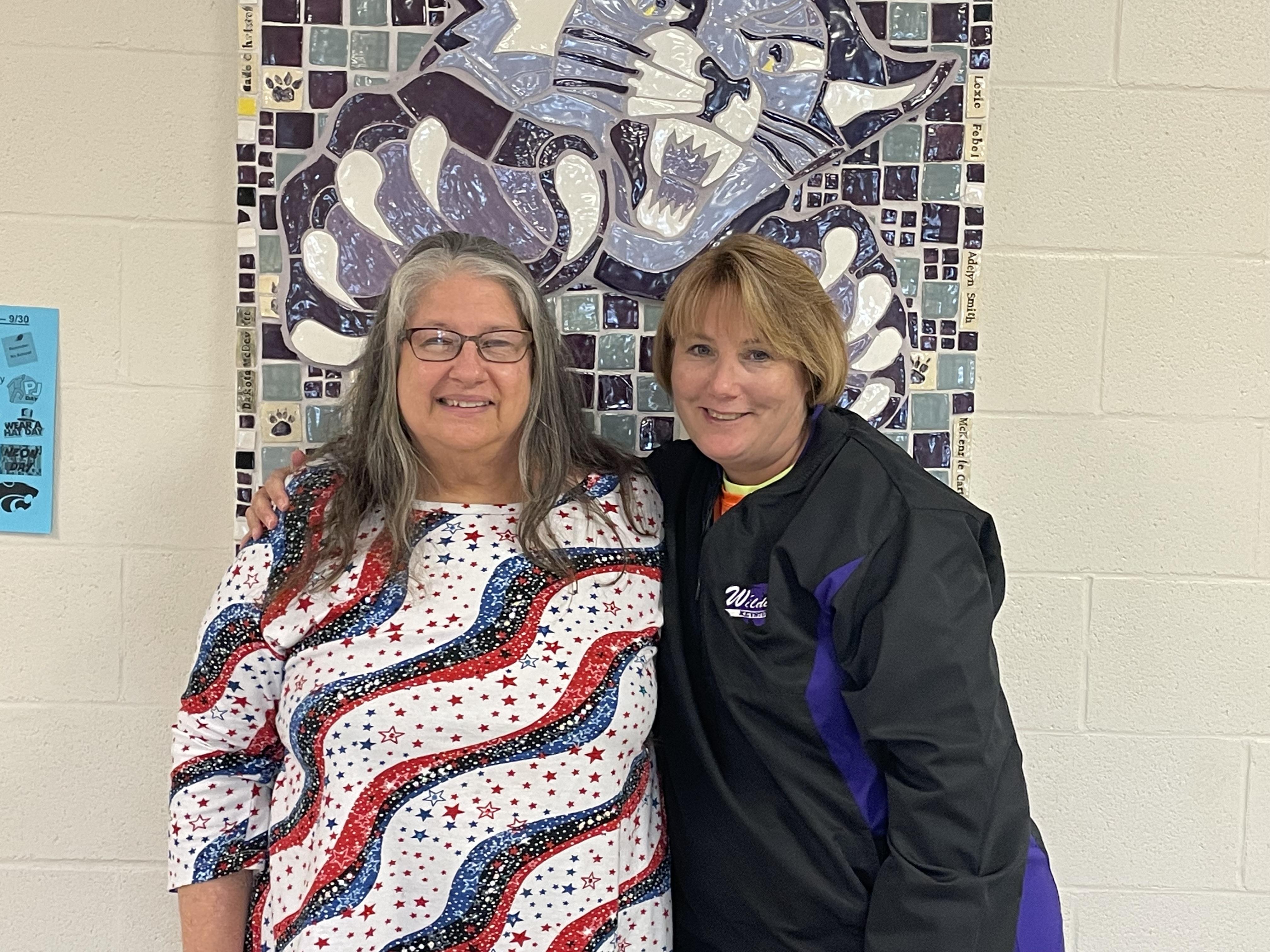 Two women standing in front of a painting