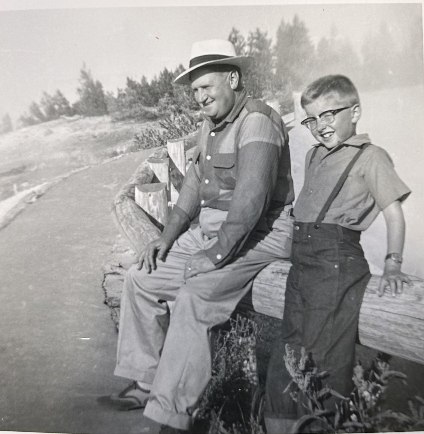 A man and boy sitting on a fence