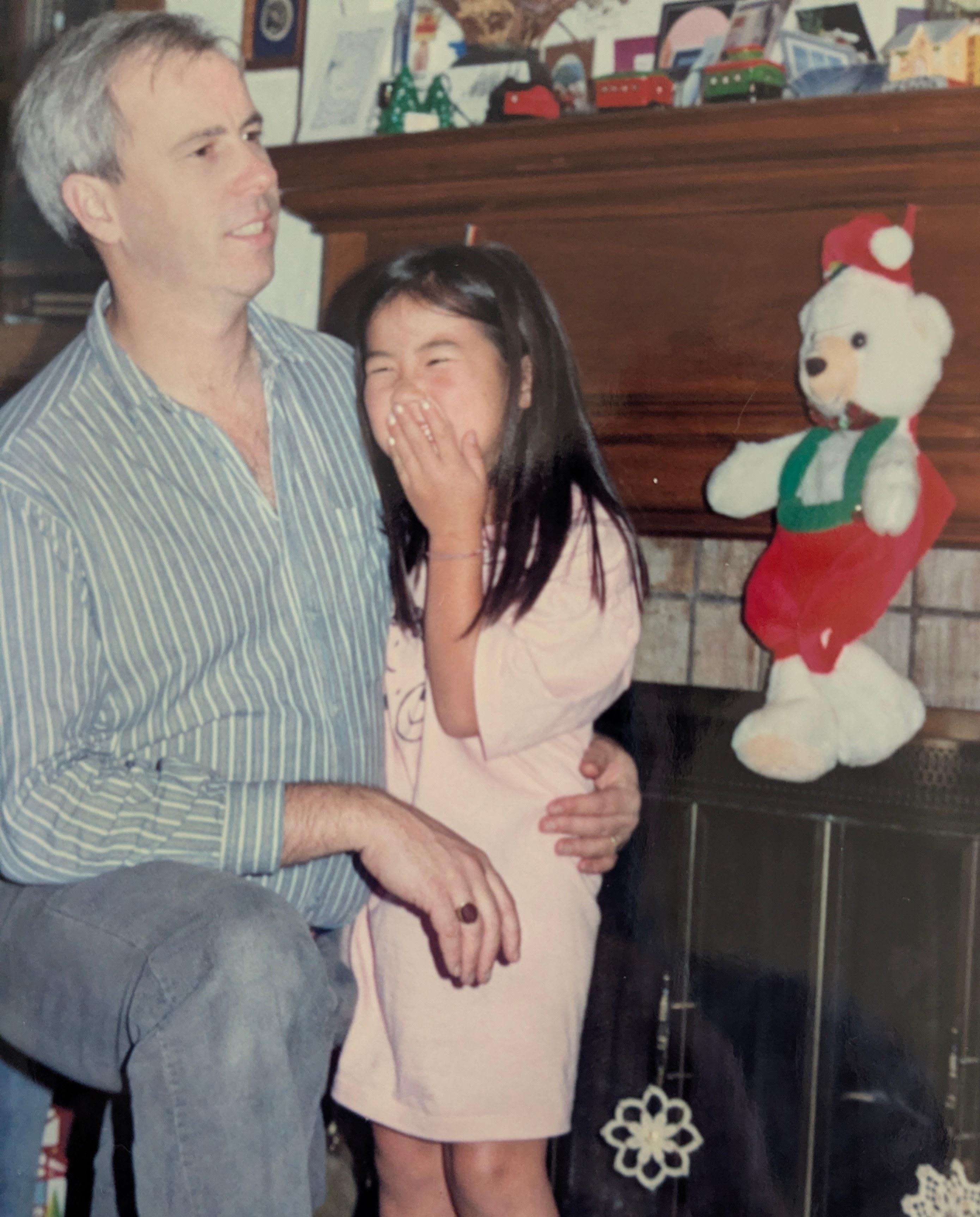 A man holding a girl with her hand over her mouth