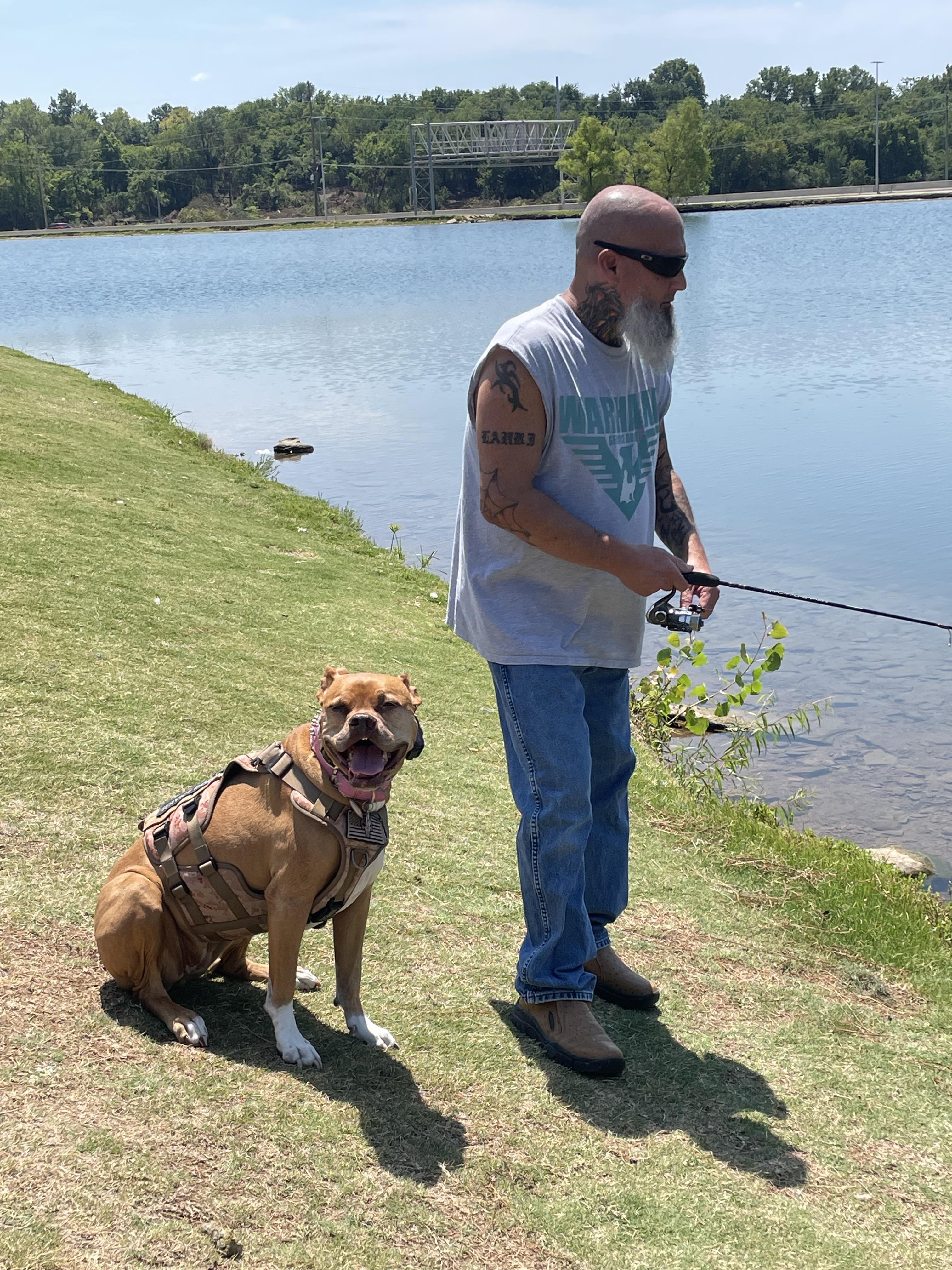 A man with a dog standing next to a body of water