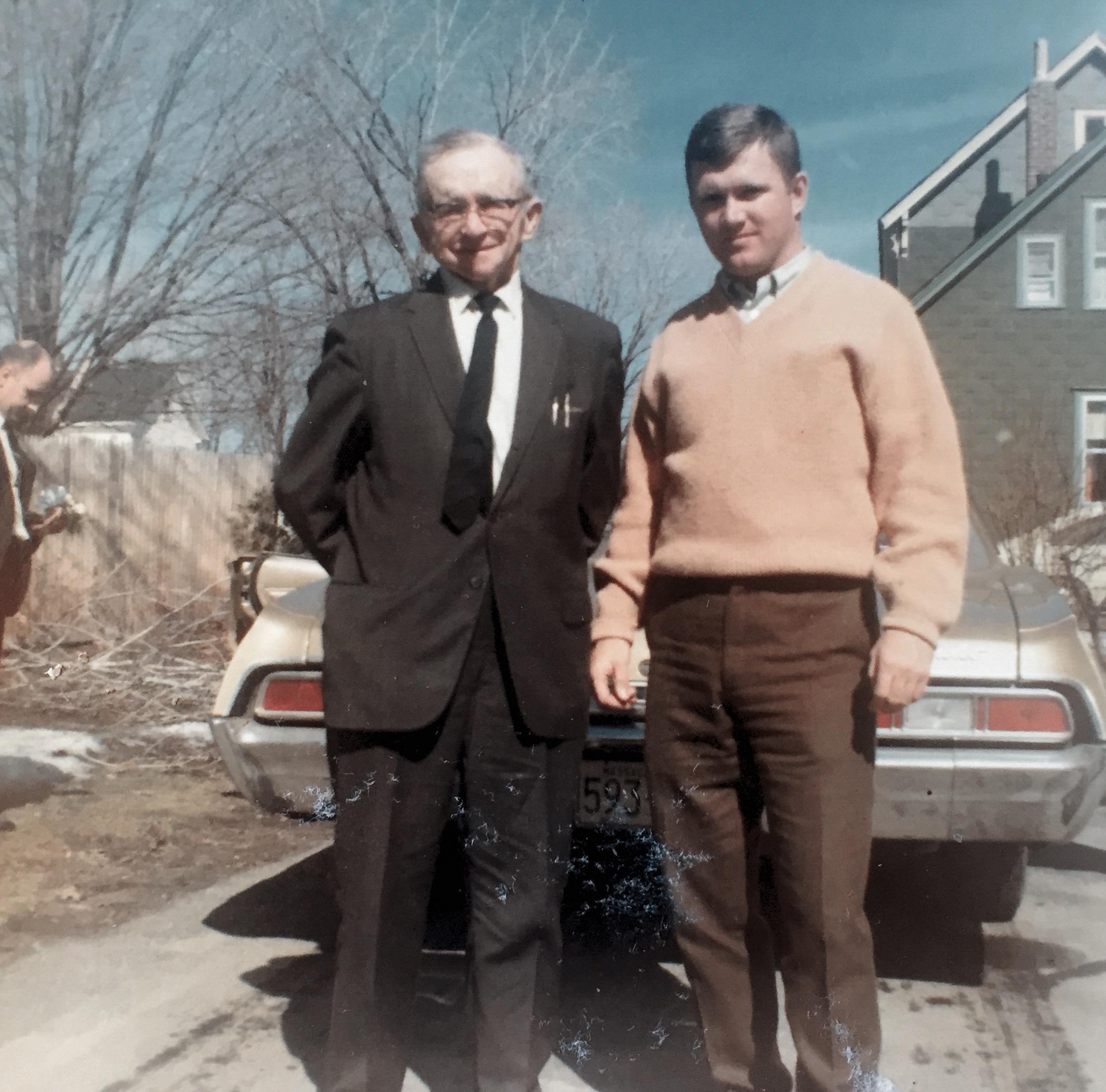 Two men standing next to a car