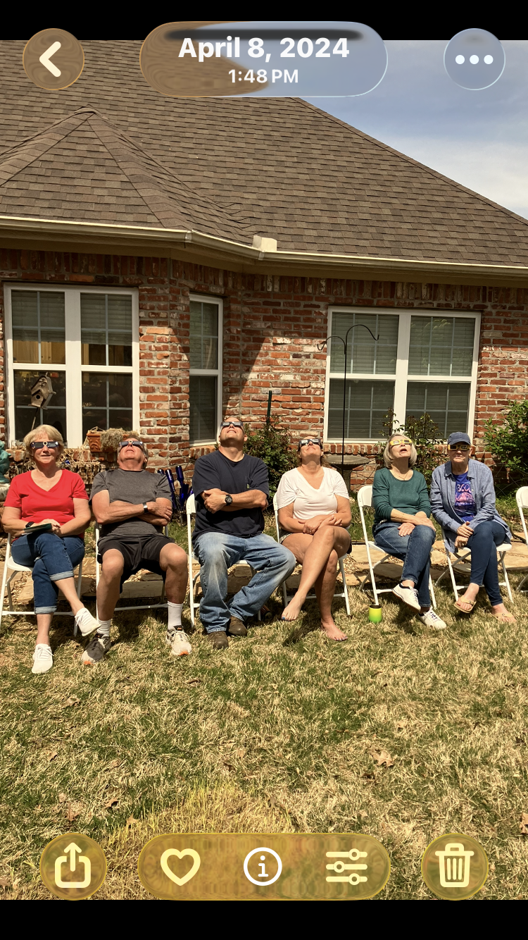 A group of people sitting in chairs outside a brick house
