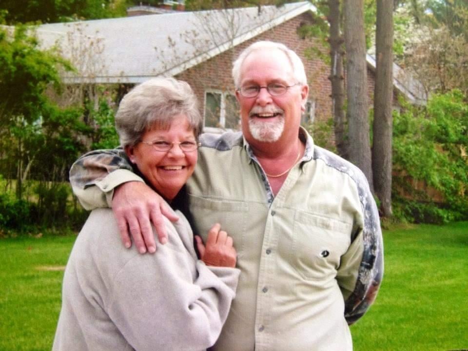 A man and woman standing in front of a house