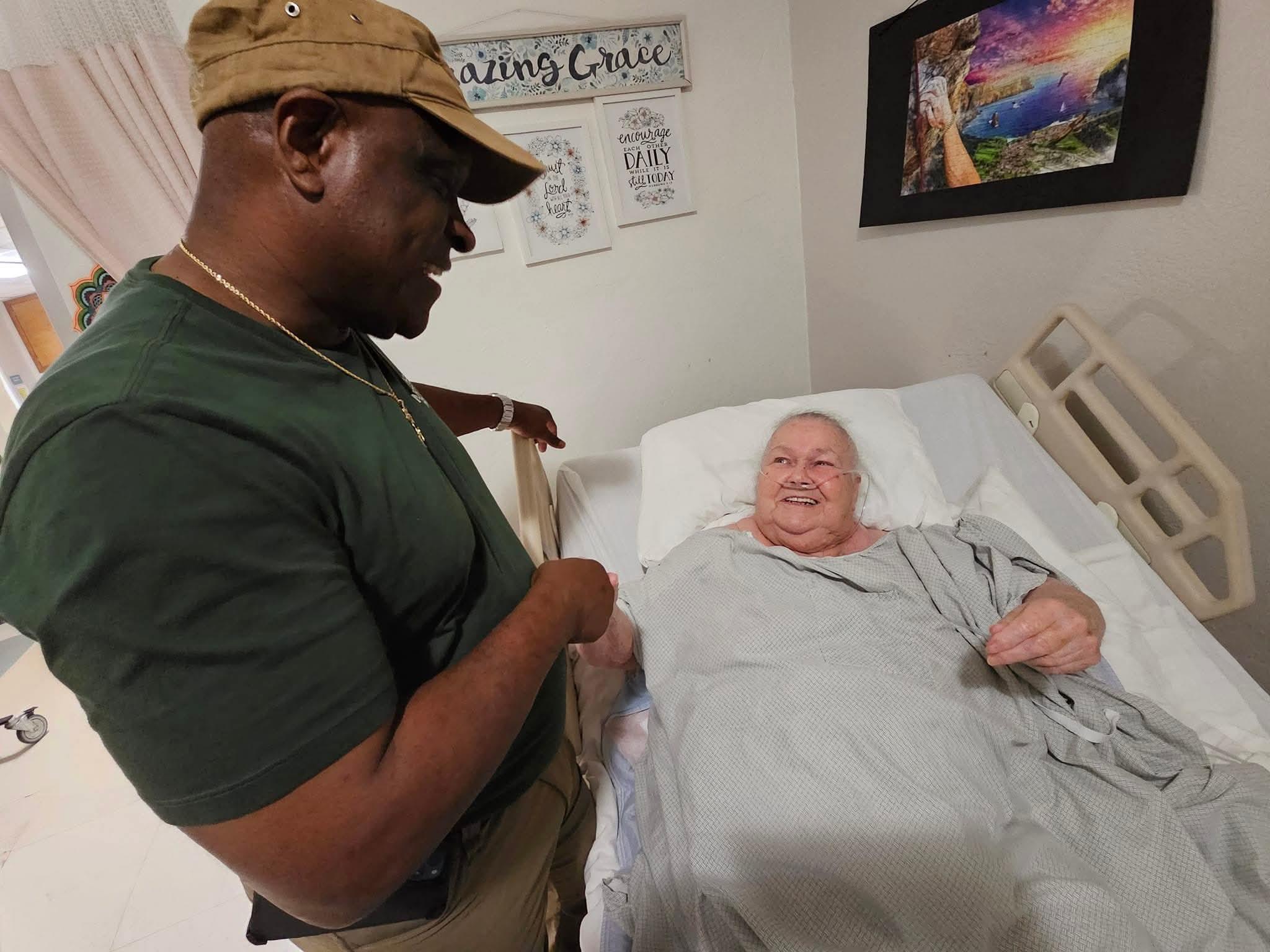 A man standing next to a man in a hospital bed