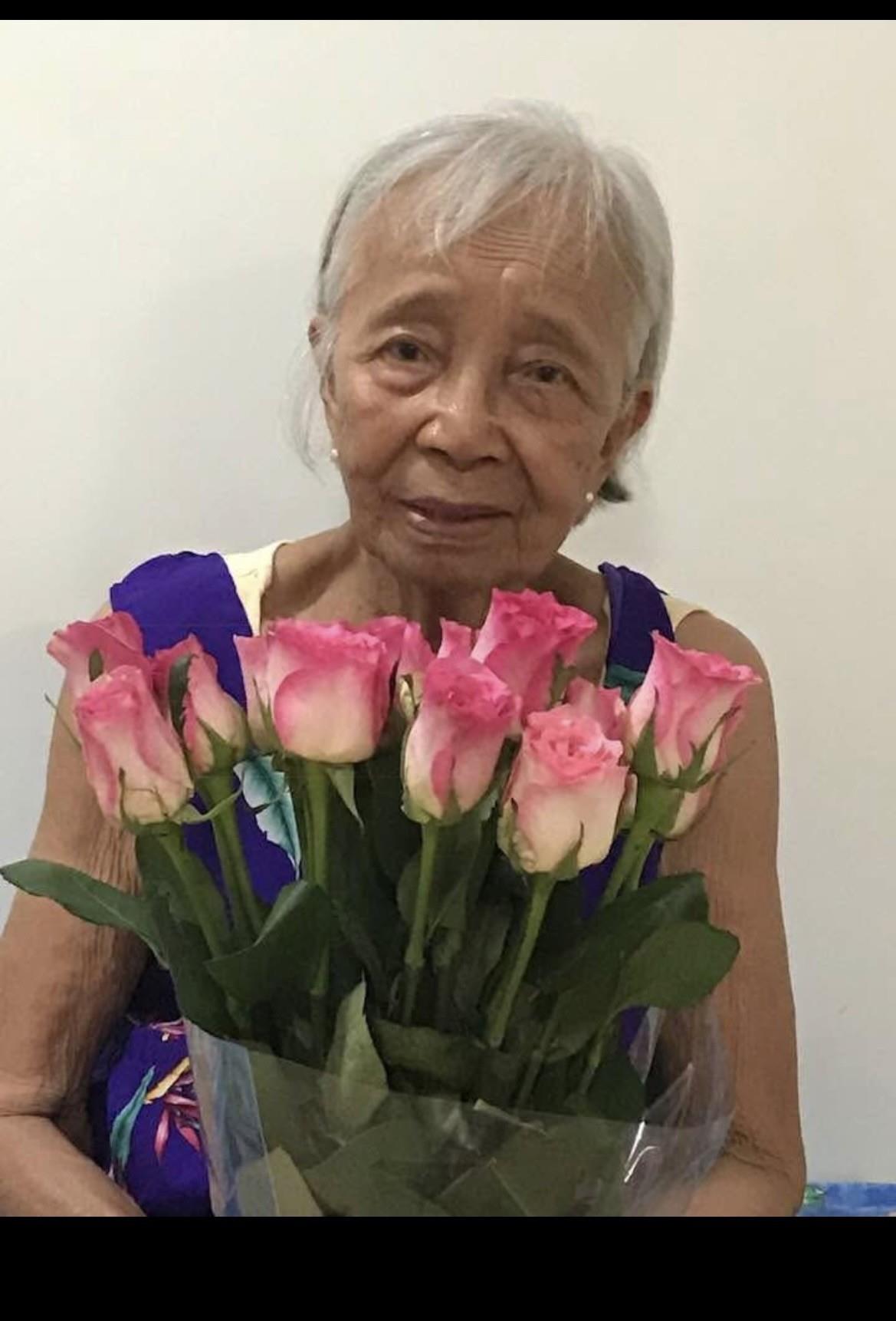 An old woman holding a bouquet of pink roses