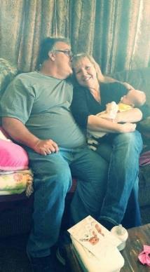 A man and woman sitting on a couch with a baby