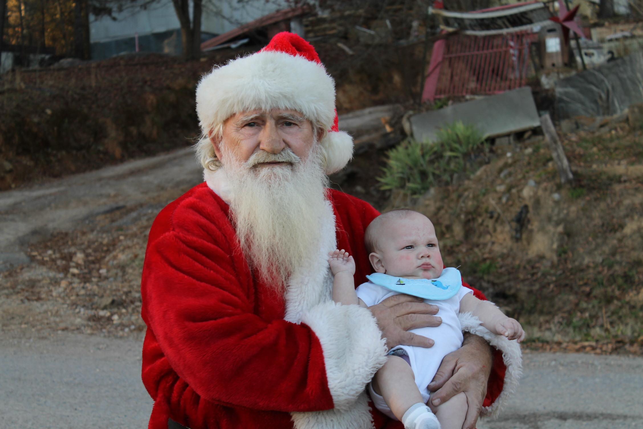 A man in a santa garment holding a baby