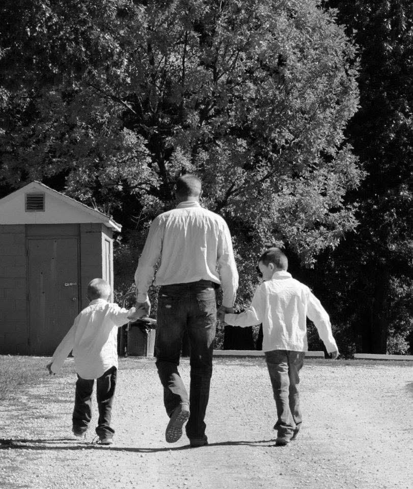A man and two boys walking on a dirt road