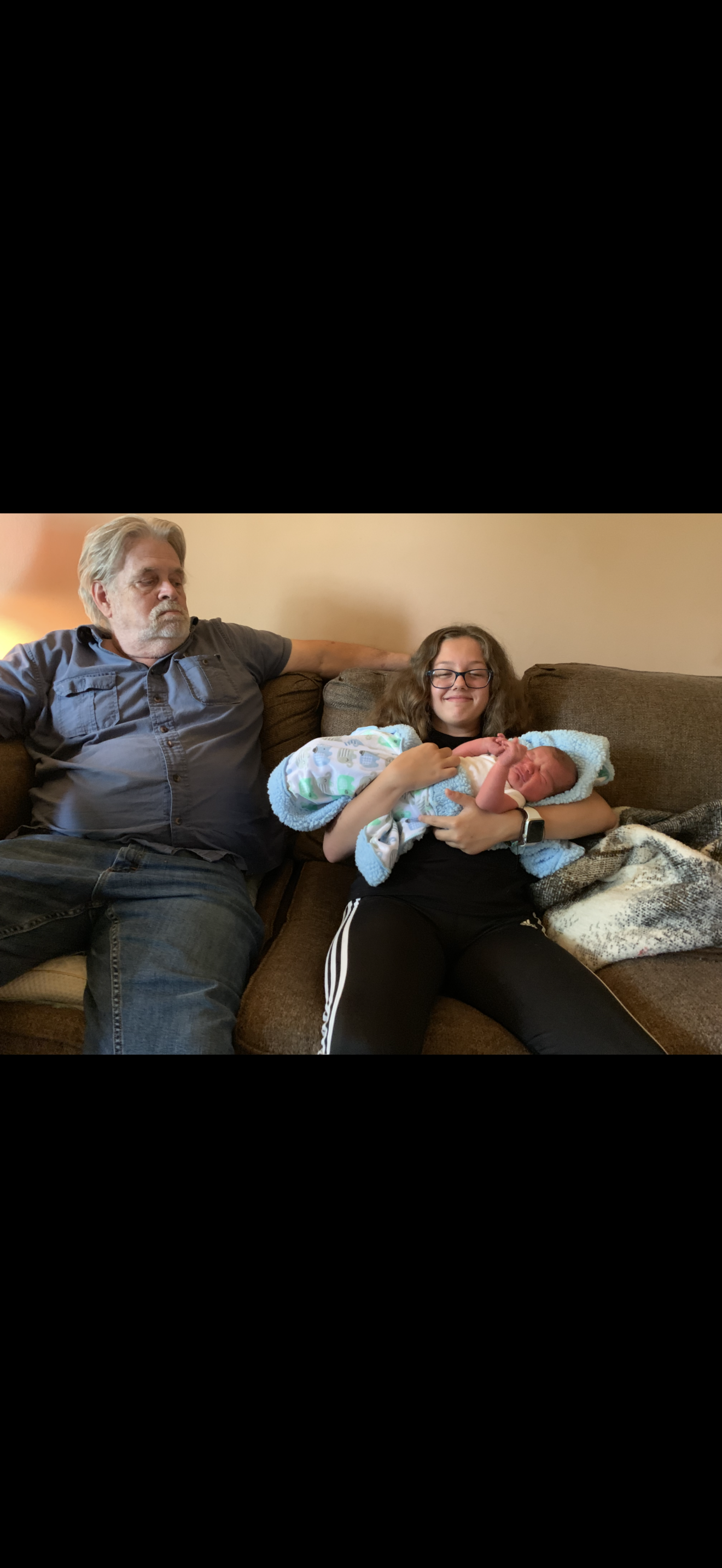 A man and woman sitting on a couch with a baby