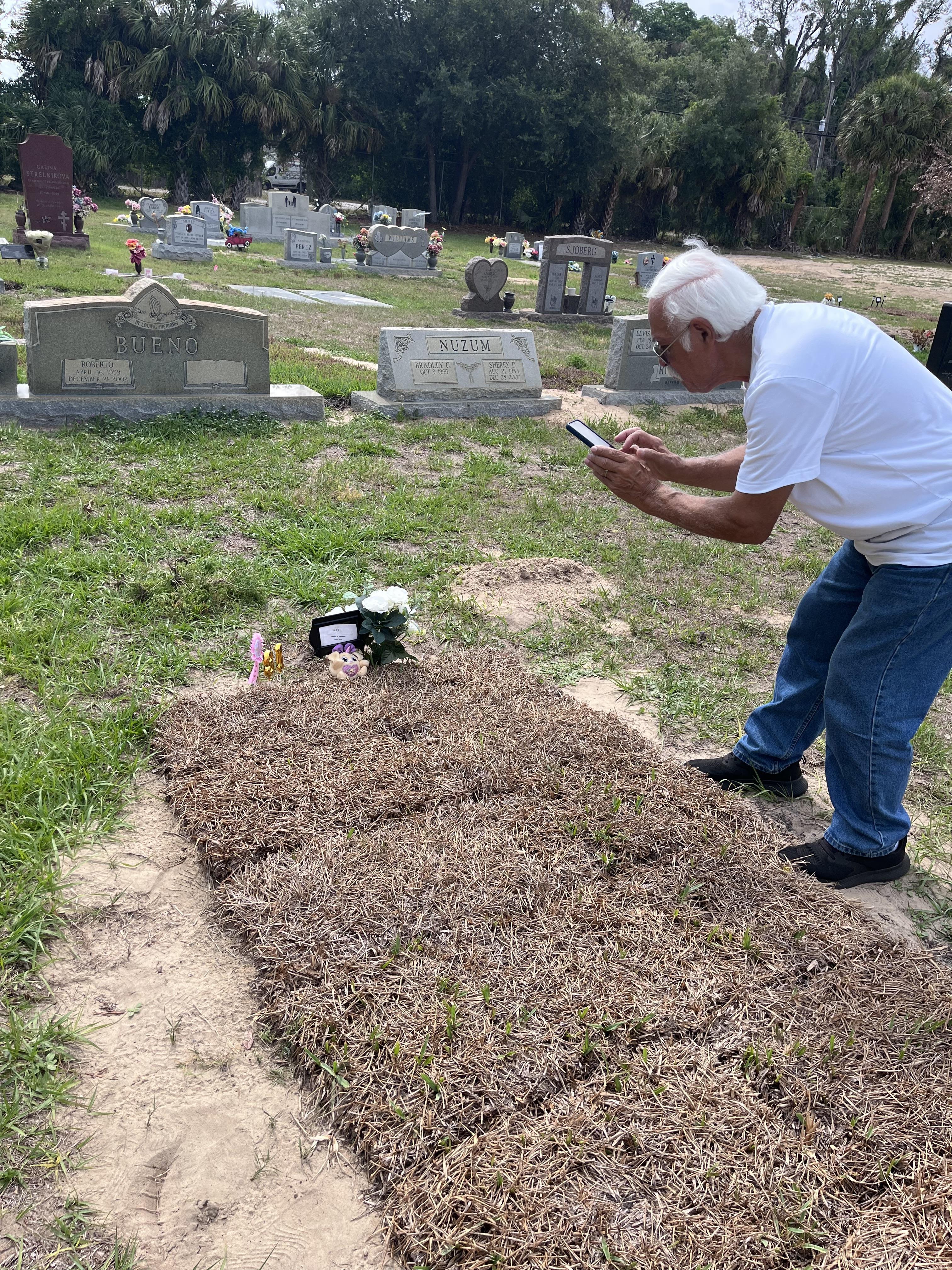 A man standing in a cemetery looking at a phone