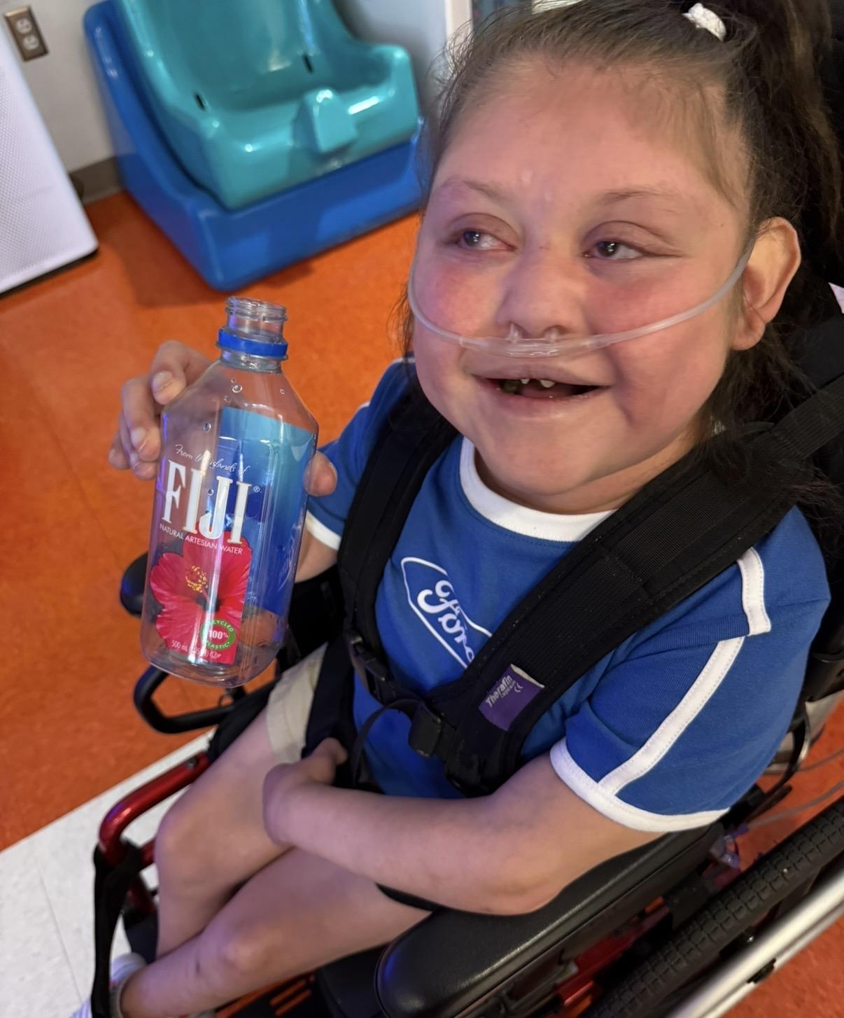 A child in a wheelchair holding a bottle of water