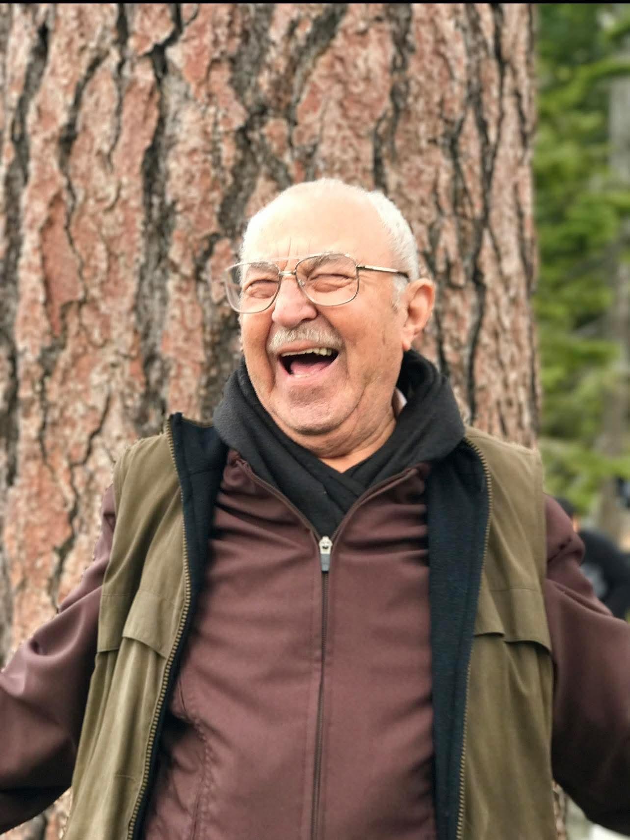 A man laughing in front of a tree