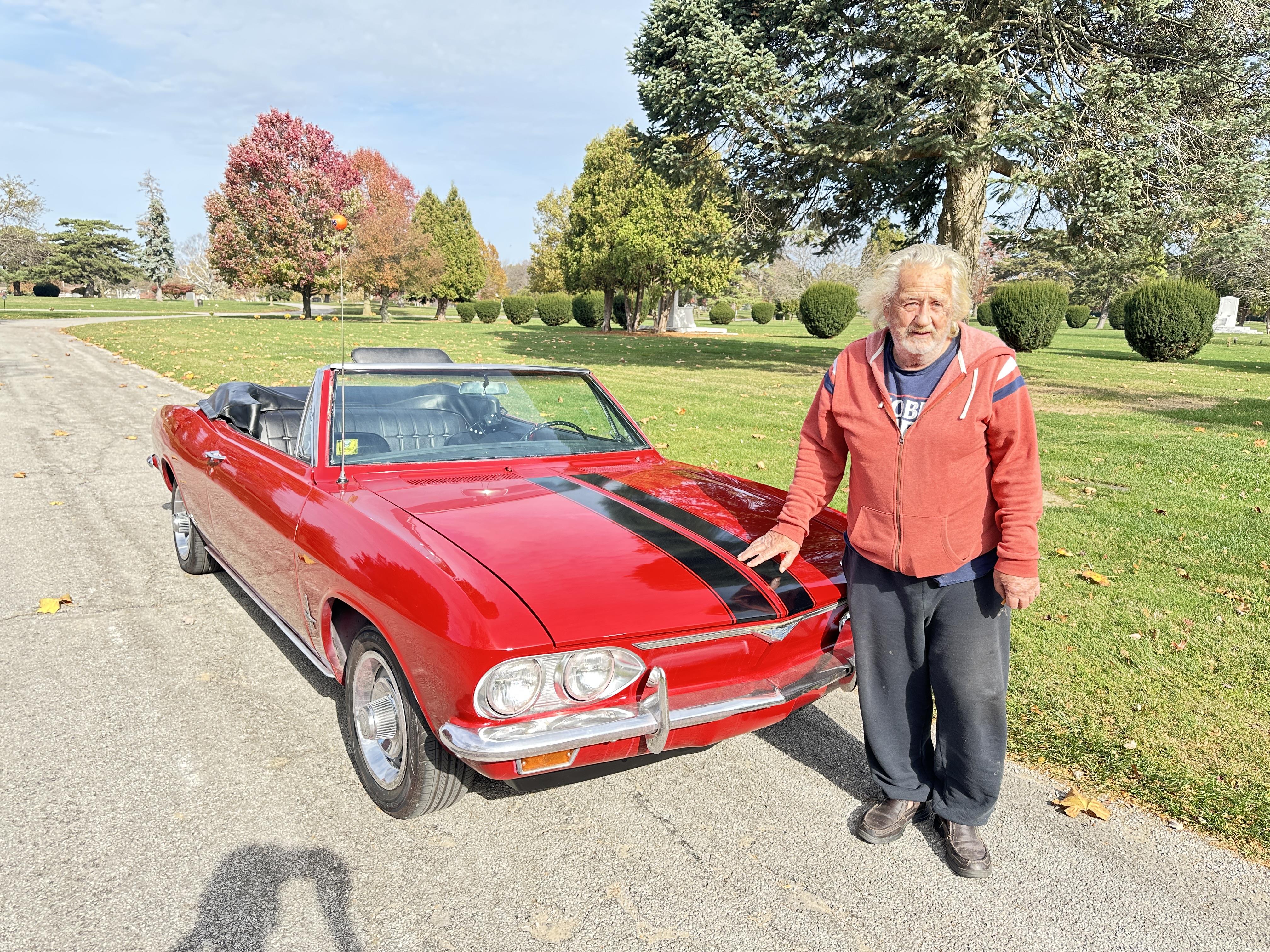 A man standing next to a red car