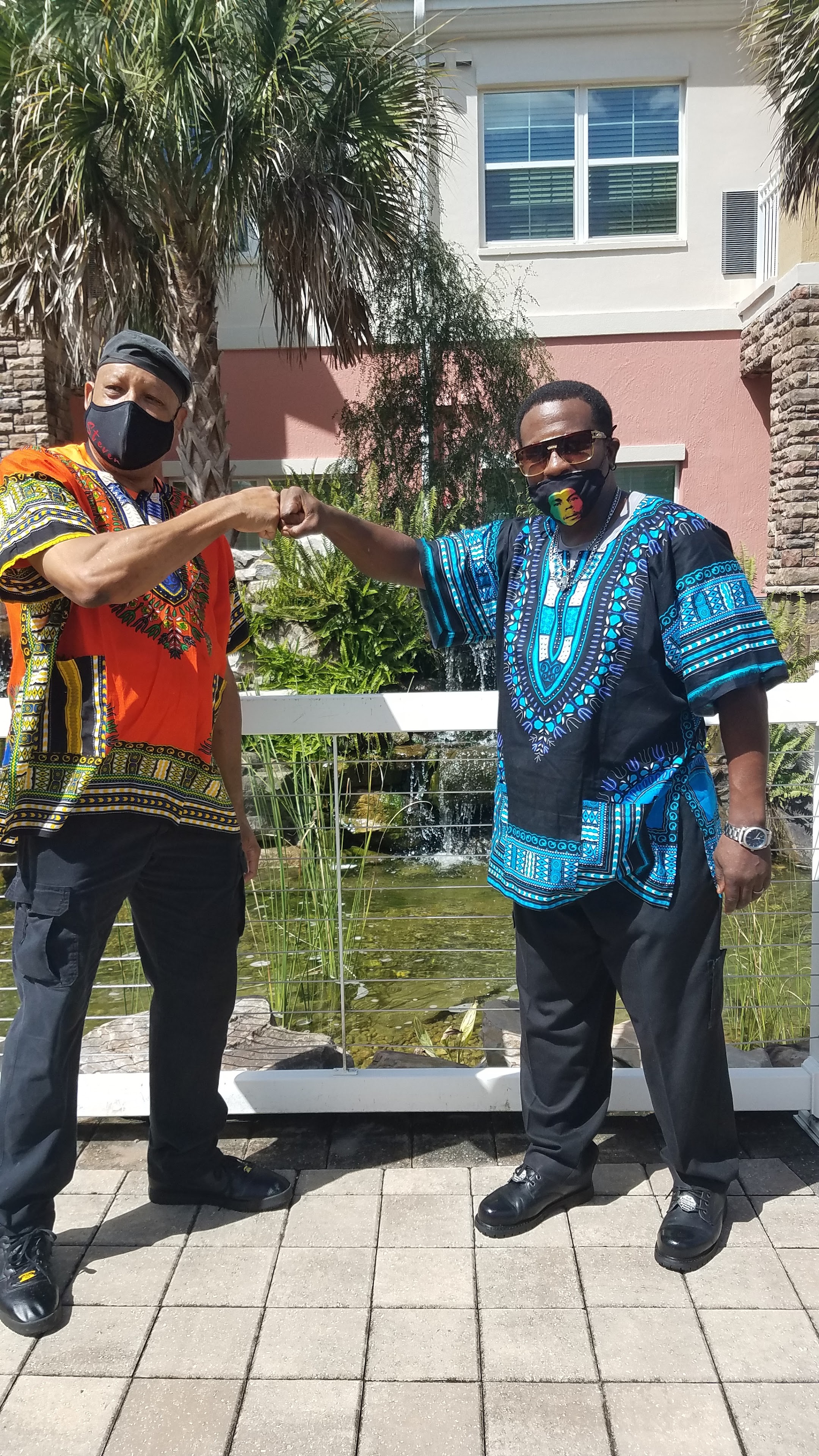 Two men wearing face masks and arm wrestling