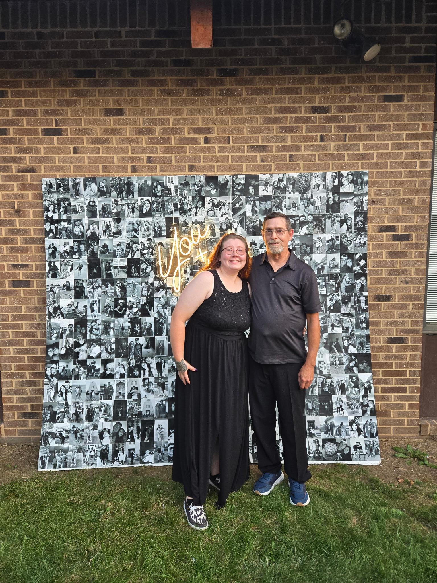 A man and woman standing in front of a wall with photos