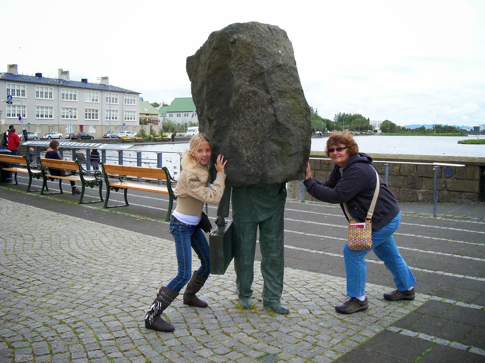 A woman pushing a large rock on a statue