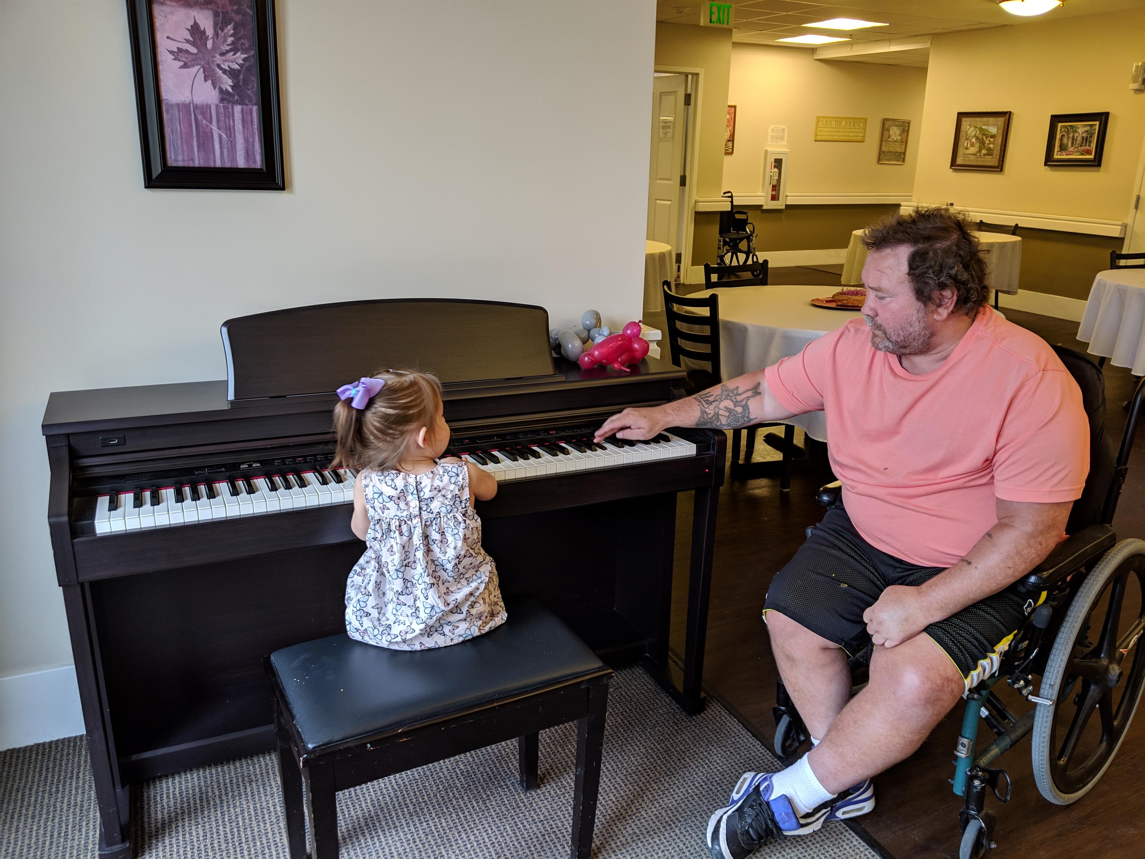 A man and a little girl playing piano