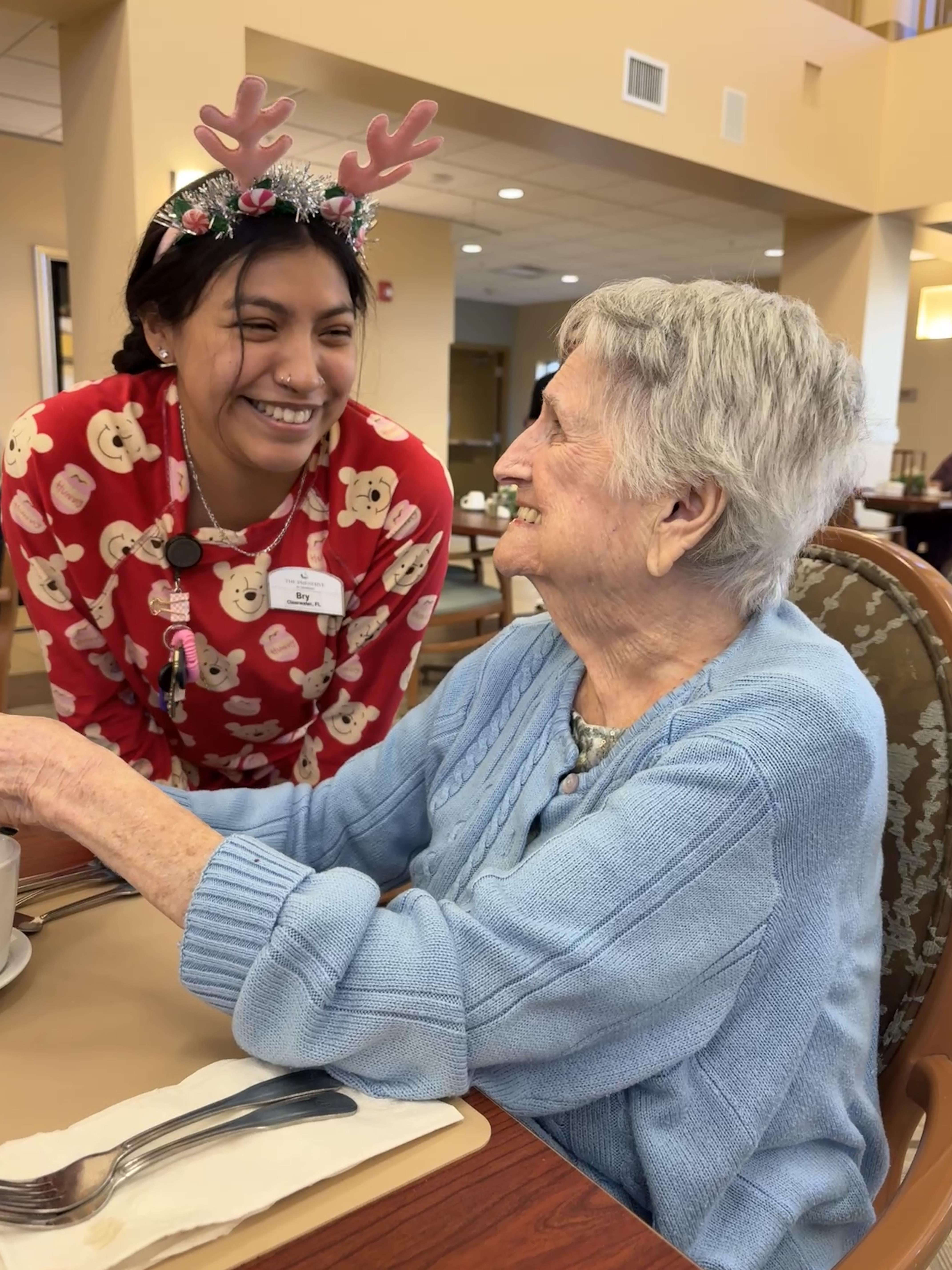 A woman smiling at an elderly woman