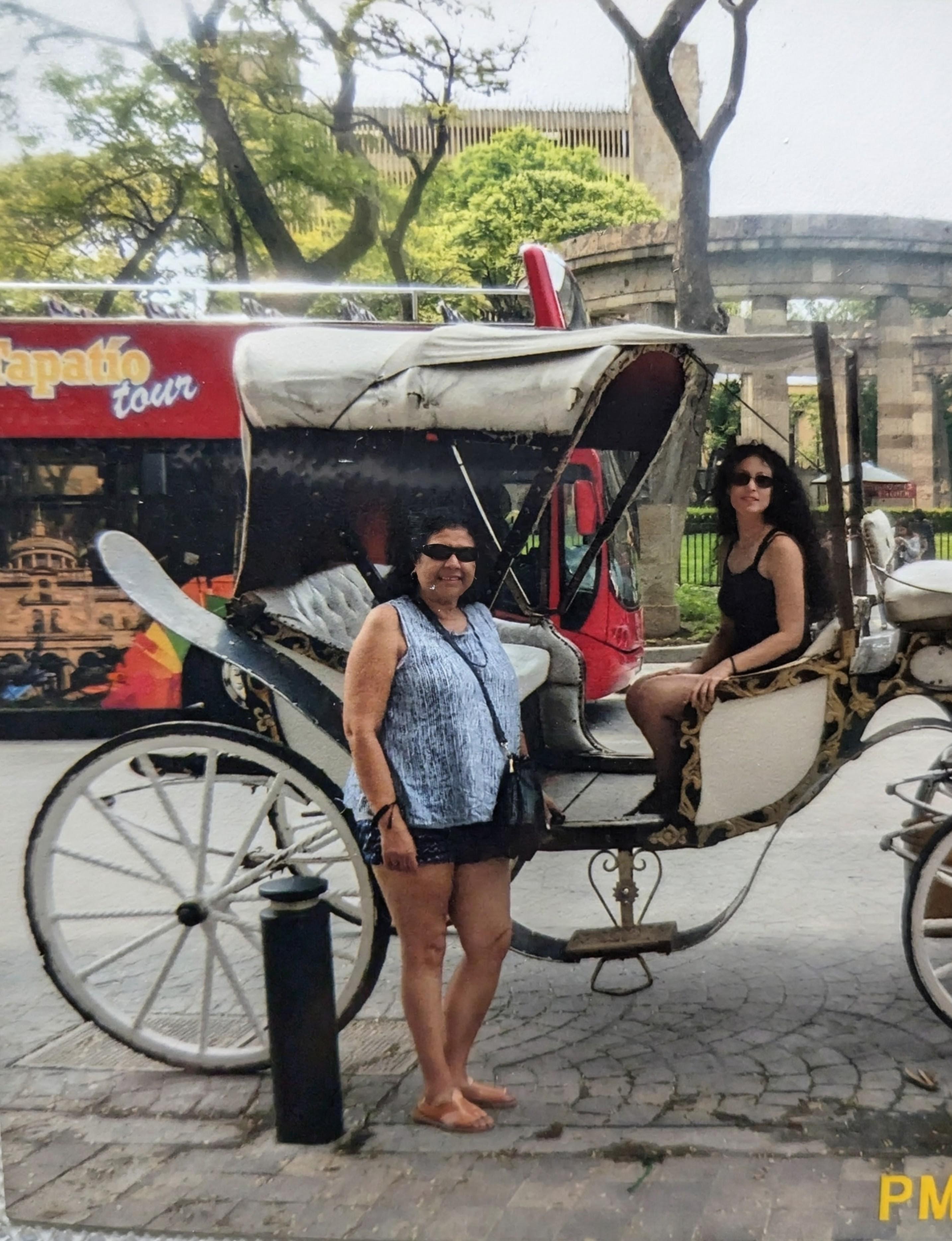 Two women standing next to a horse carriage