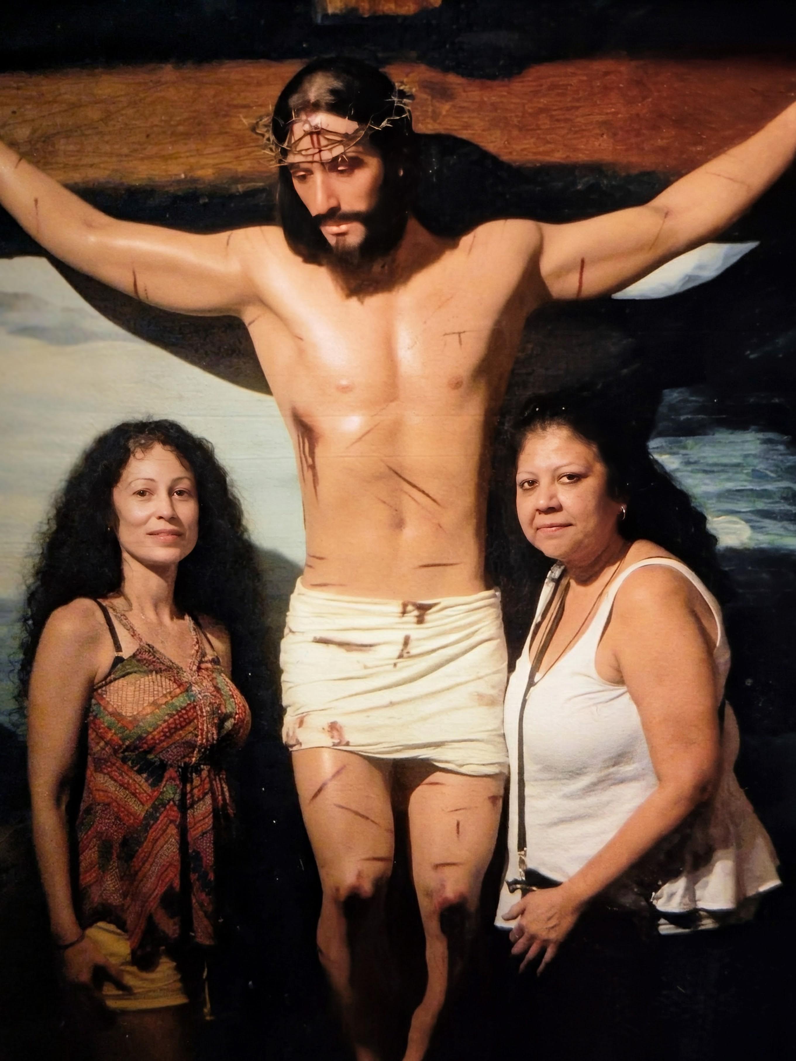 A woman standing next to a statue of a man crucified