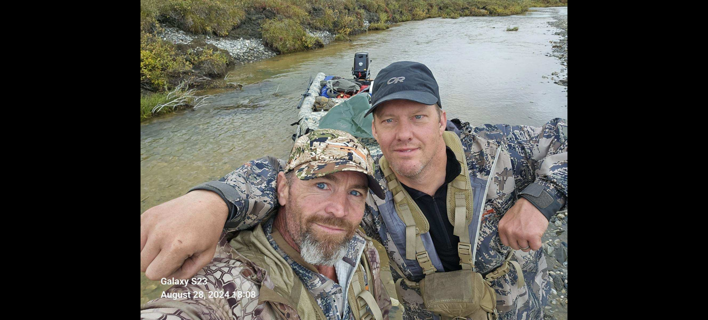 Two men in camouflage standing in a river