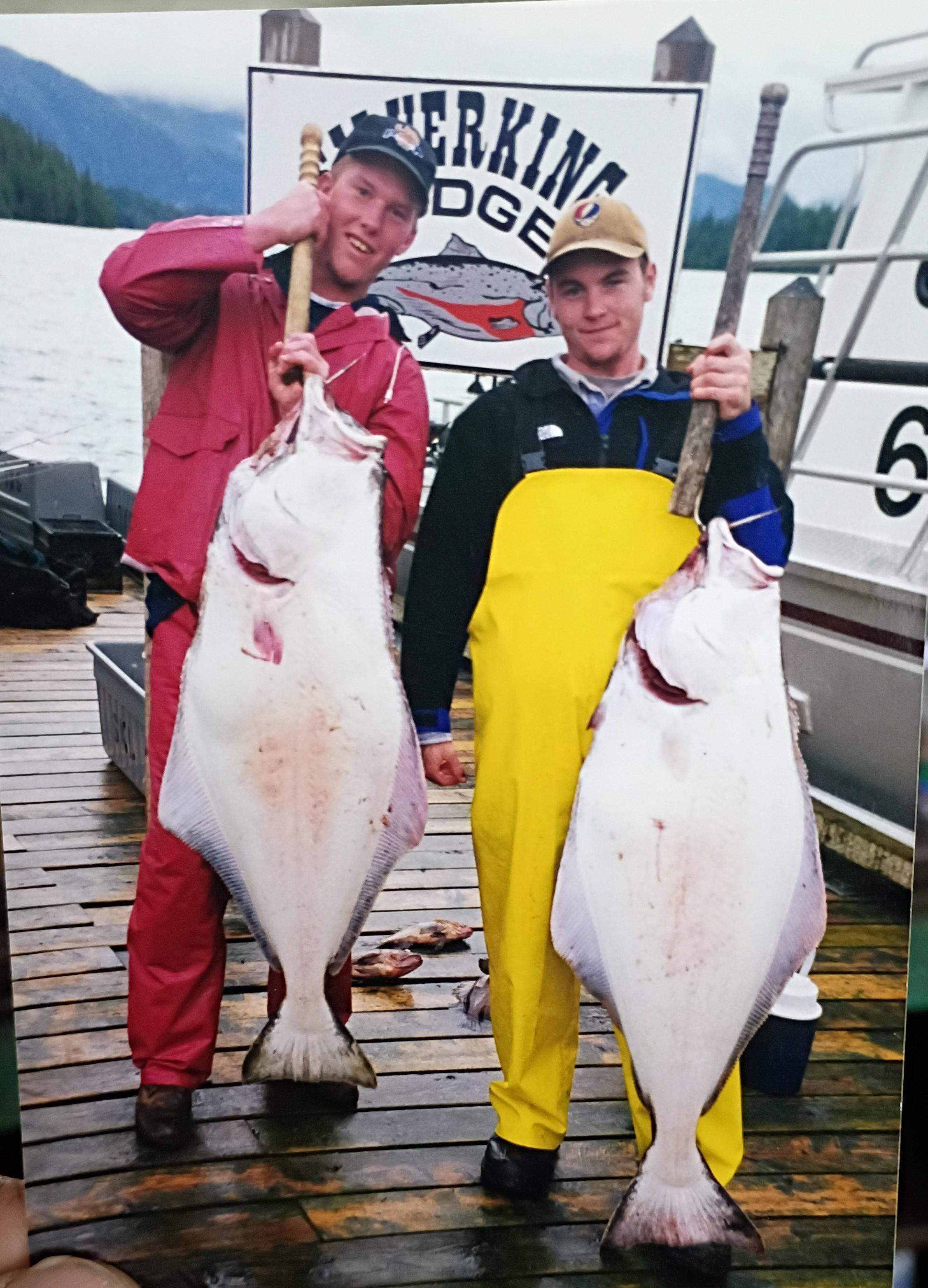 Two men holding fish on a dock