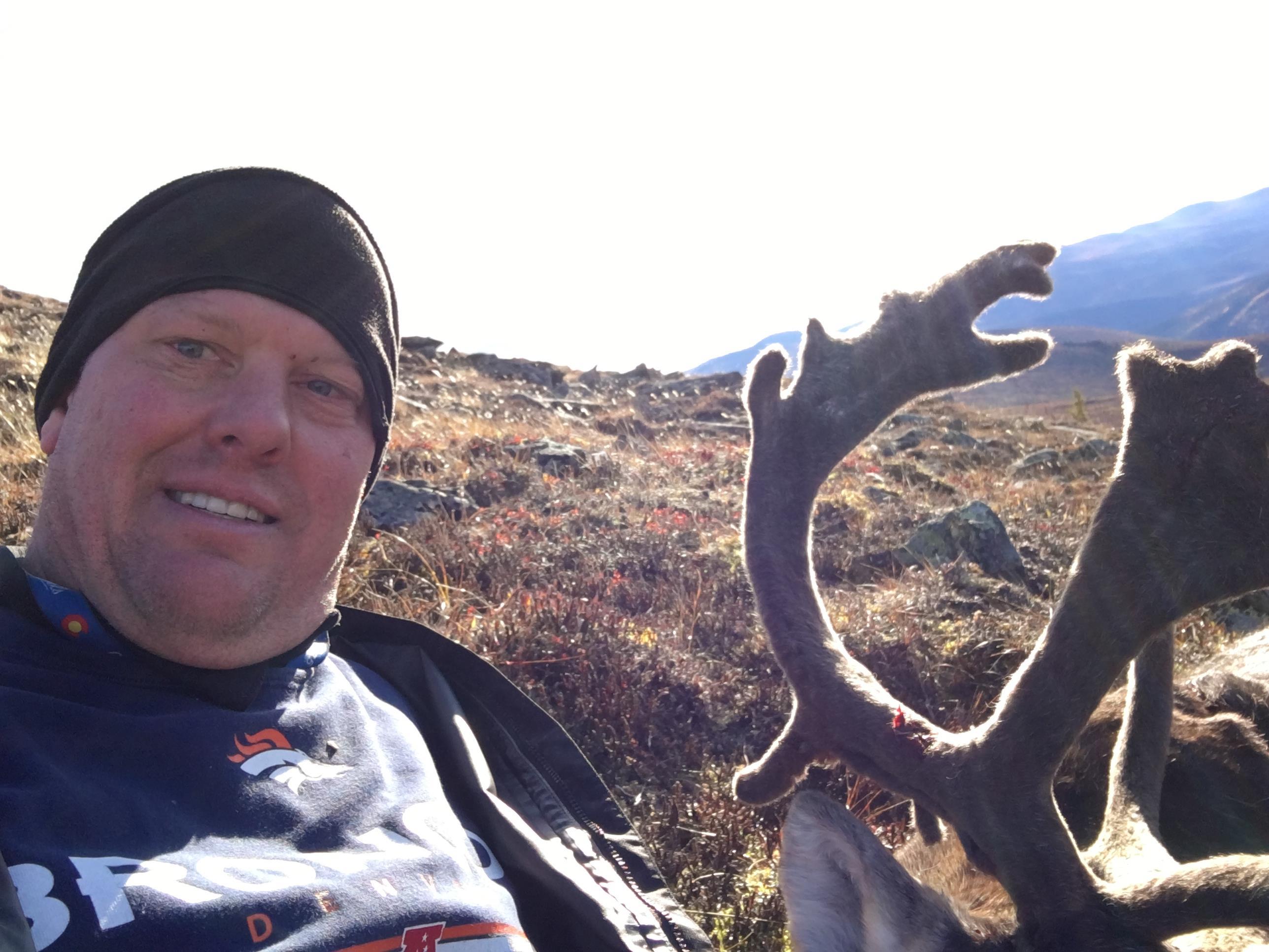 A man taking a selfie with a deer antlers