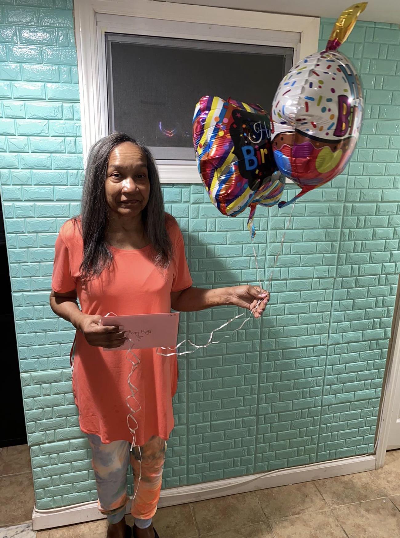 A woman holding balloons and a card