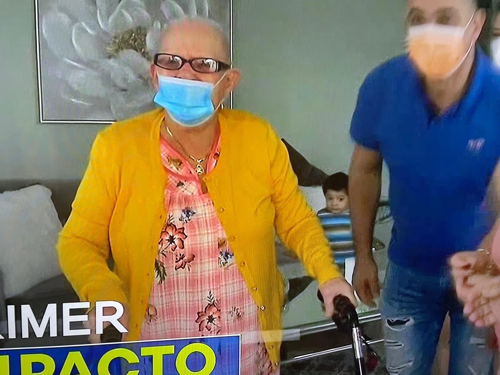 A woman wearing a mask and walking with a walker