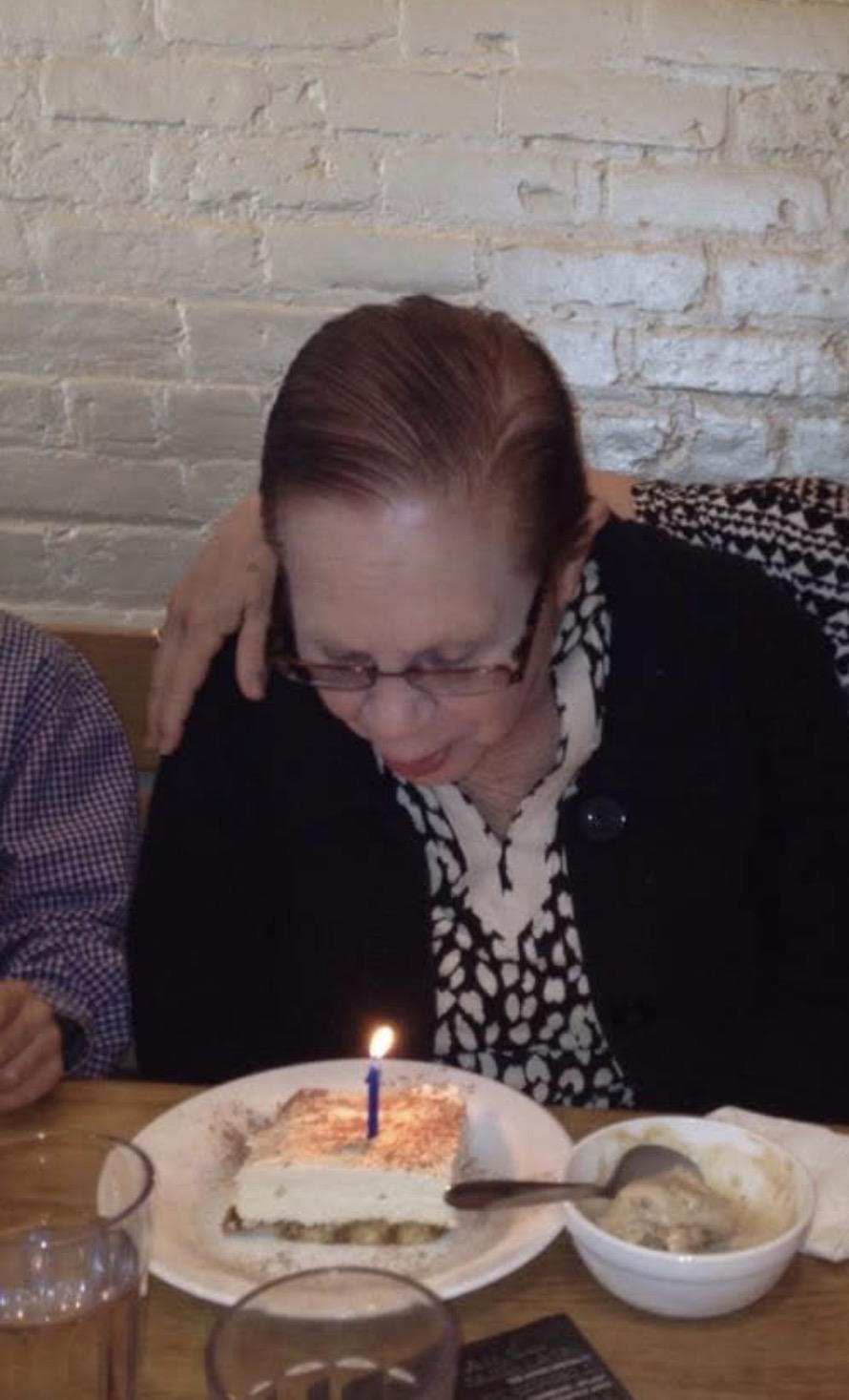A woman sitting at a table with a cake and a candle