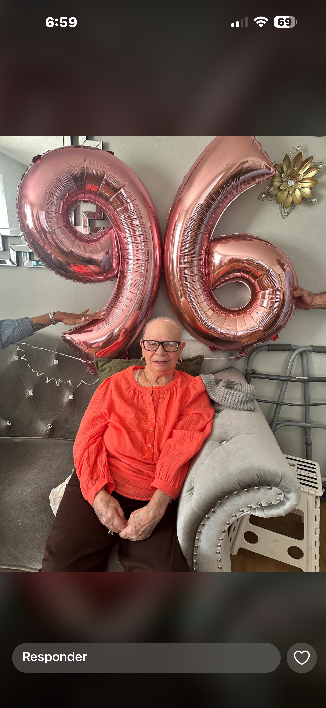 A woman sitting on a couch with balloons in the shape of a number