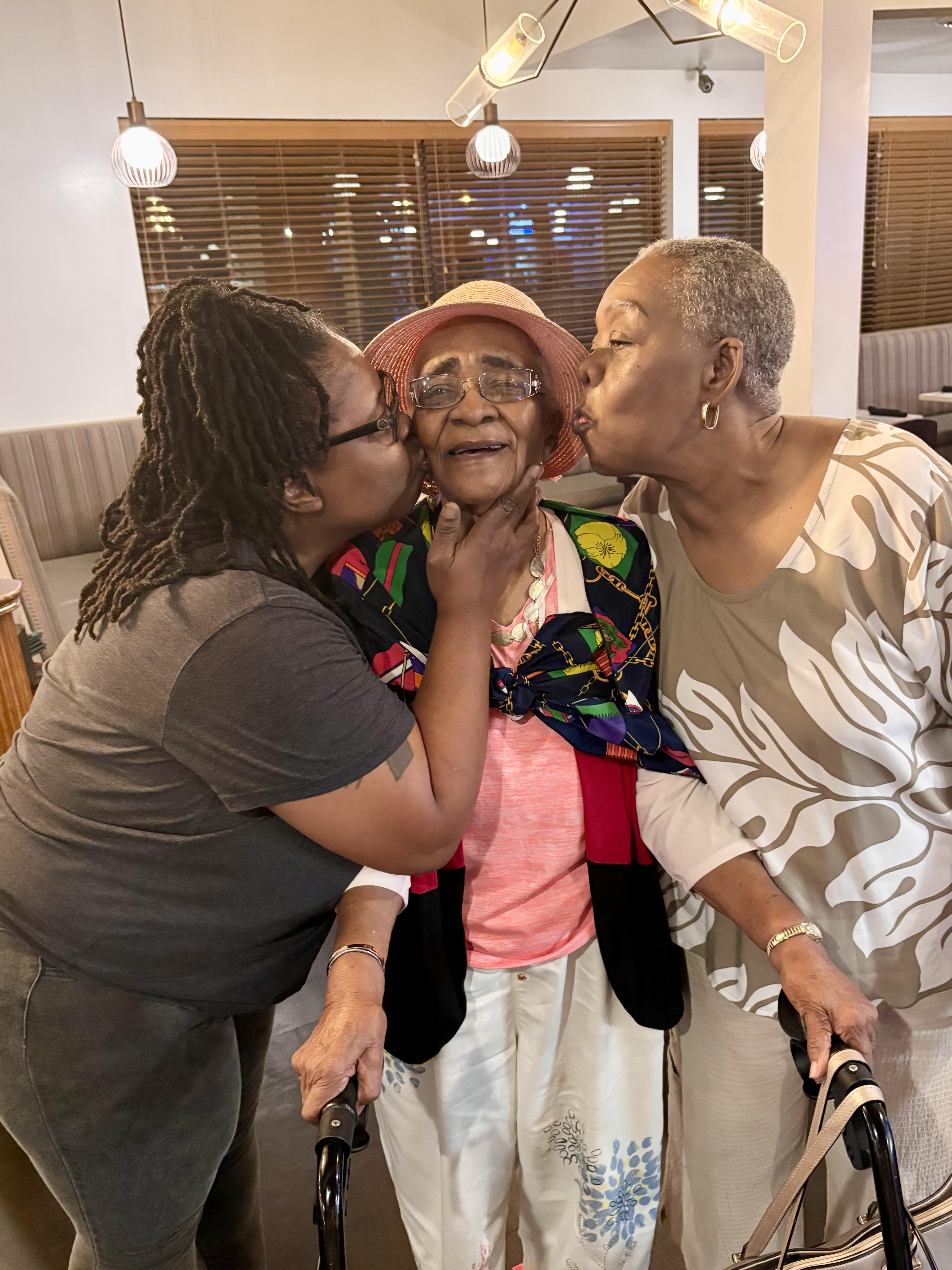 A group of women kissing an older woman