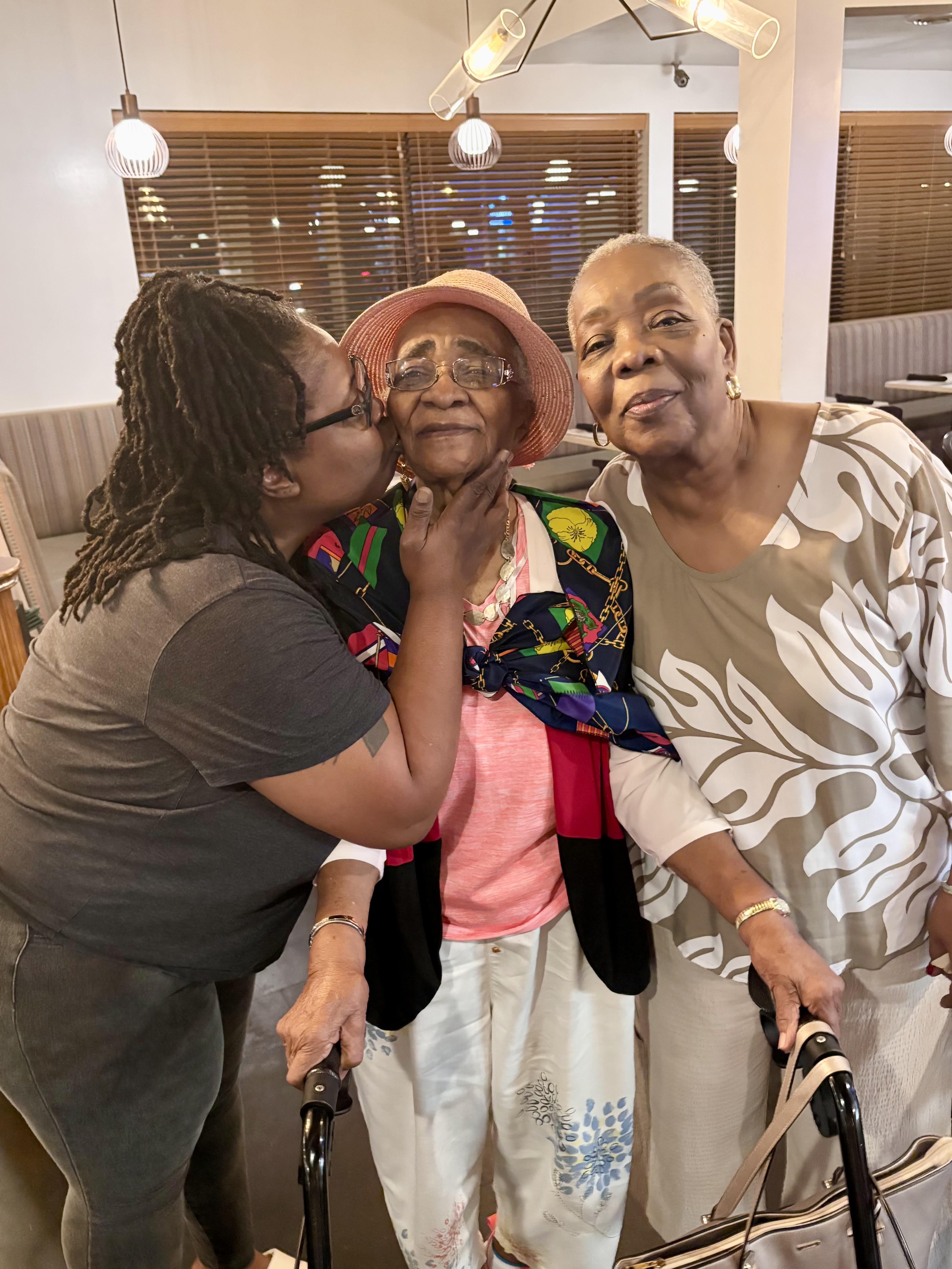 A group of women kissing a woman on the cheek