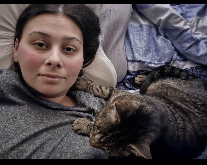 A woman lying on a bed with a cat