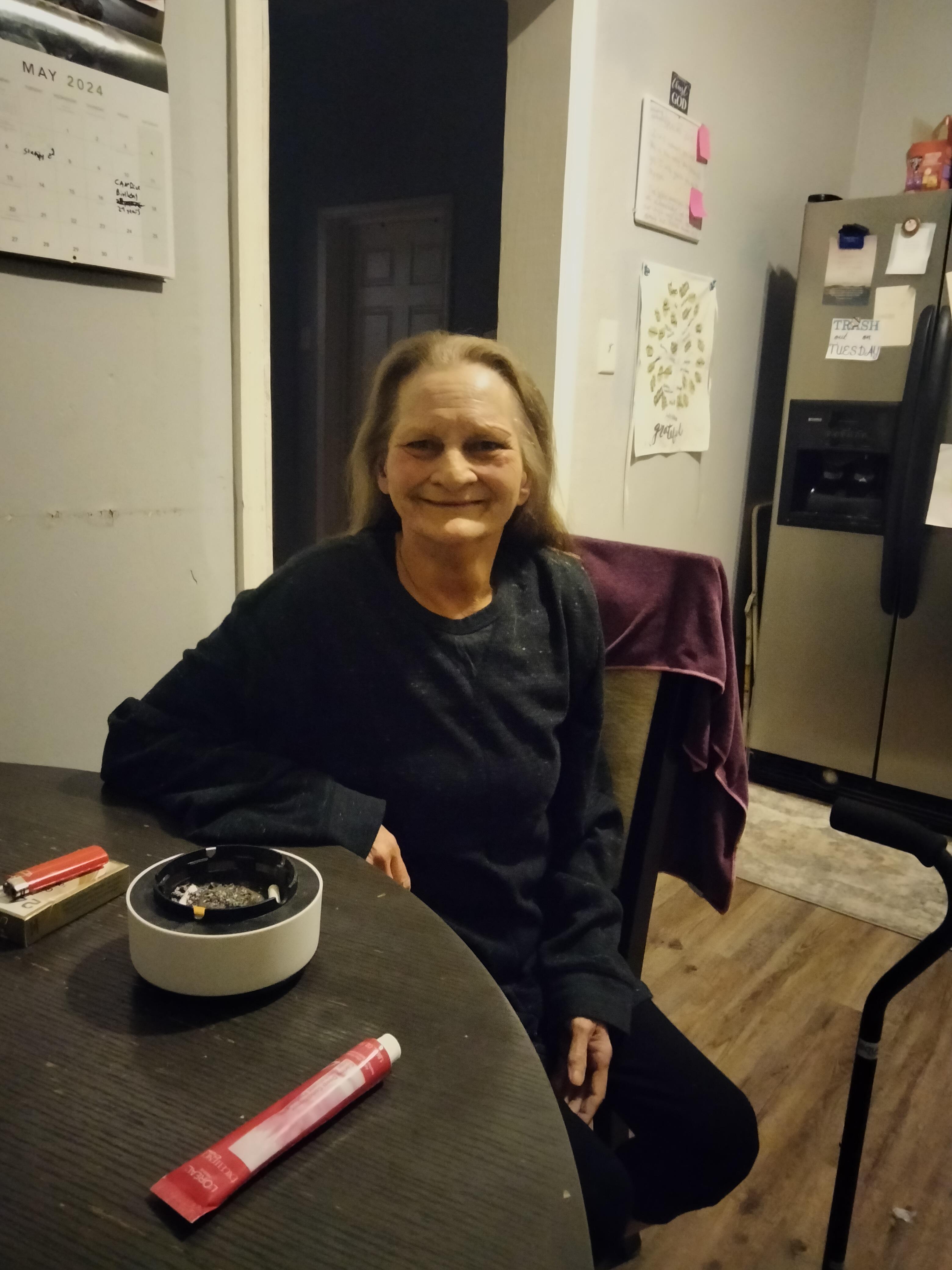 A woman sitting at a table with a ashtray