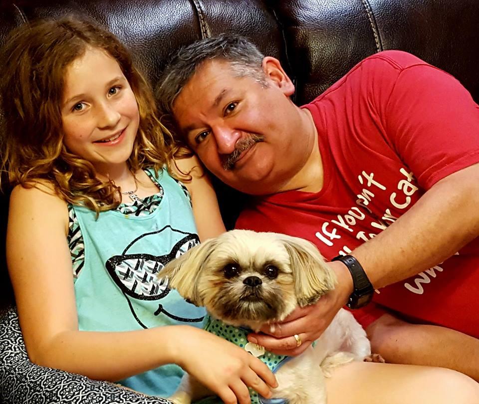 A man and girl sitting on a couch with a dog