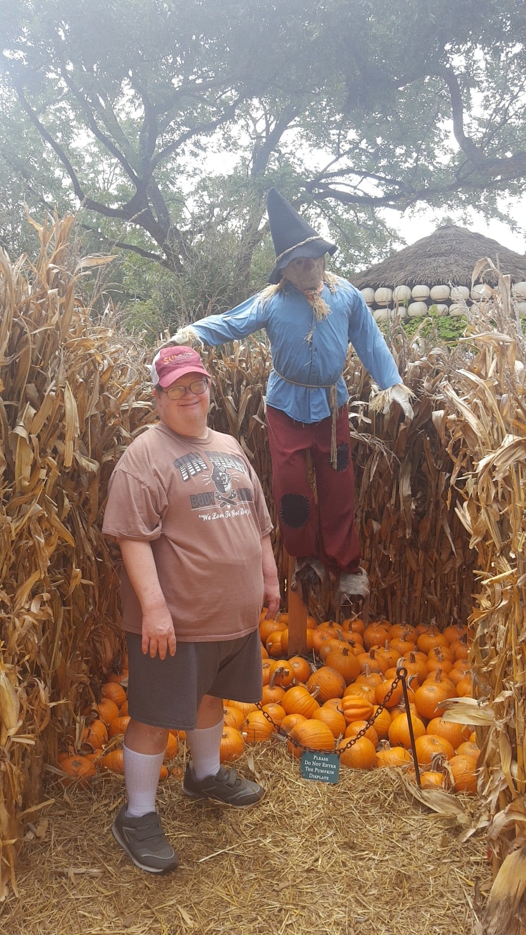 Two people standing in a corn field with a scarecrow