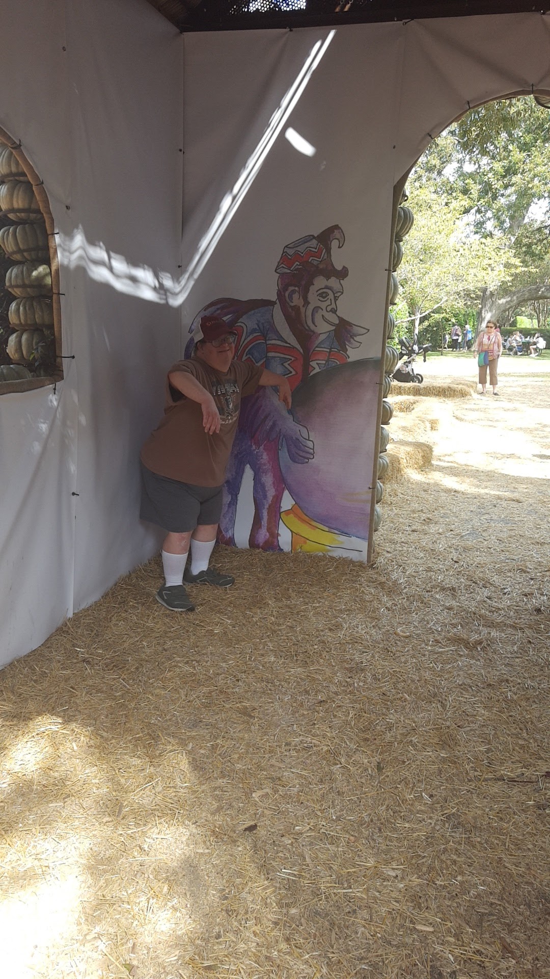 A person standing in a corner of a wall with a clown painted on it