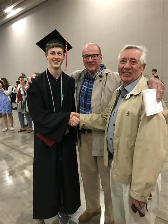 A man shaking hands with a man in a graduation cap