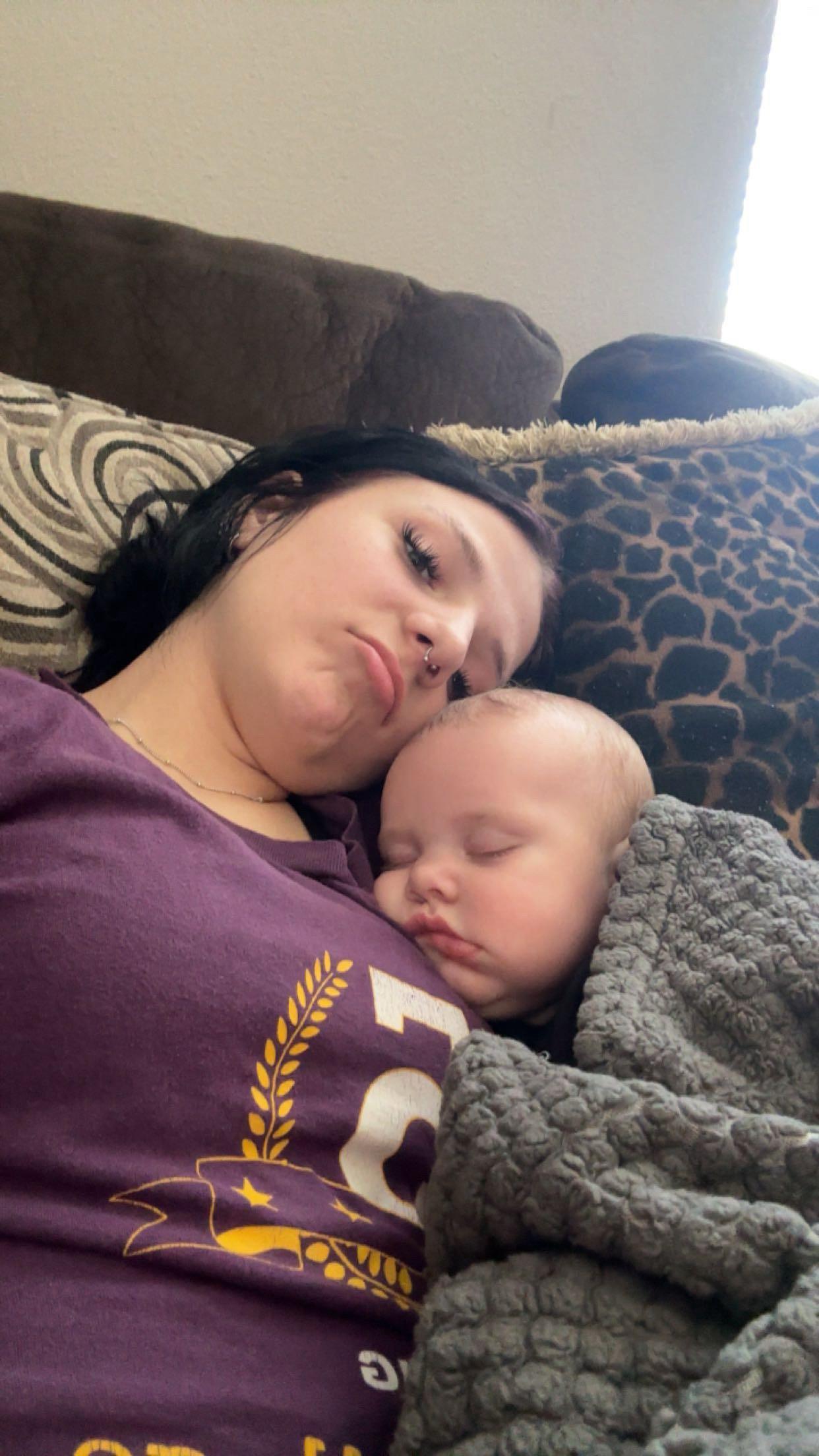 A woman lying on a couch holding a baby