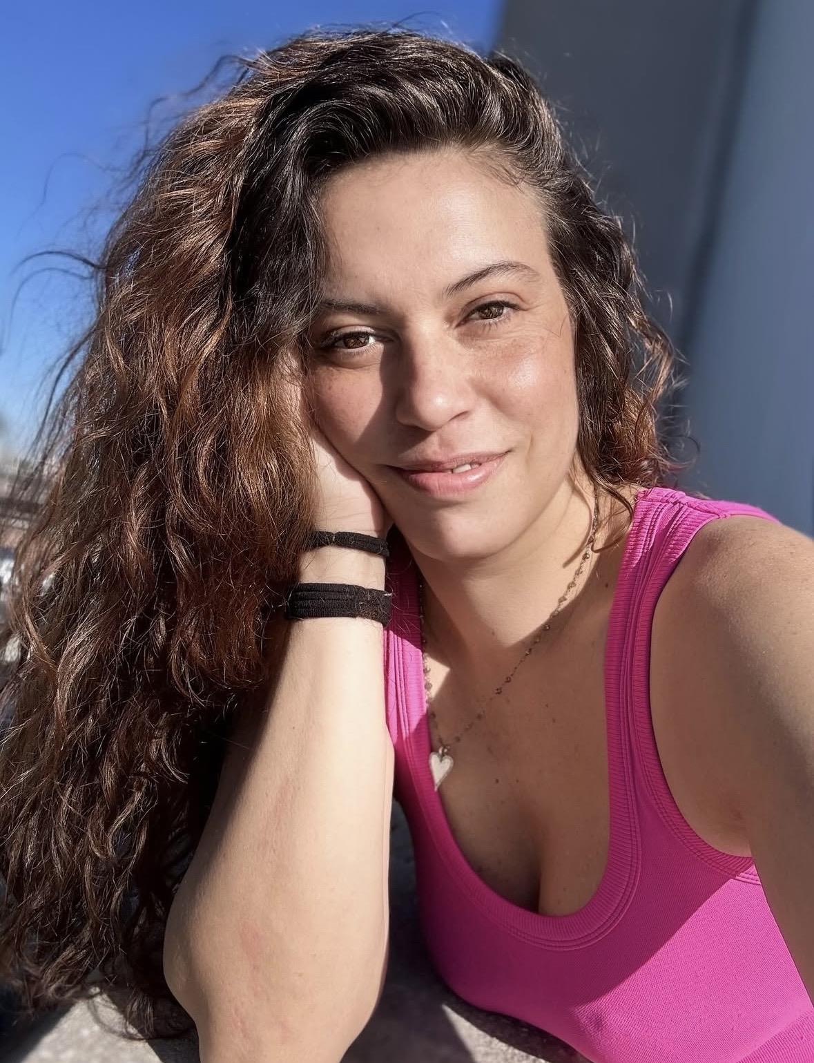 A woman with long hair wearing a pink tank top