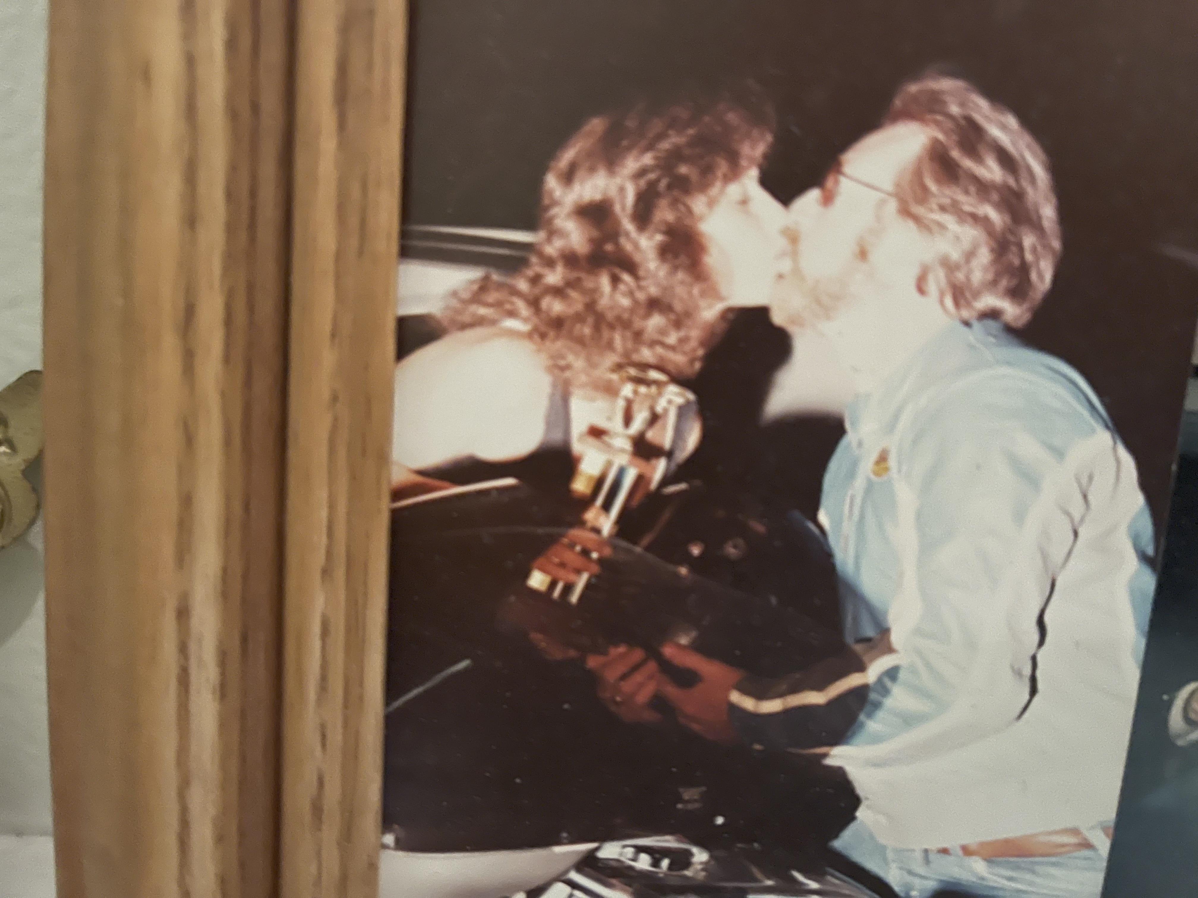 A man and woman kissing on a motorcycle