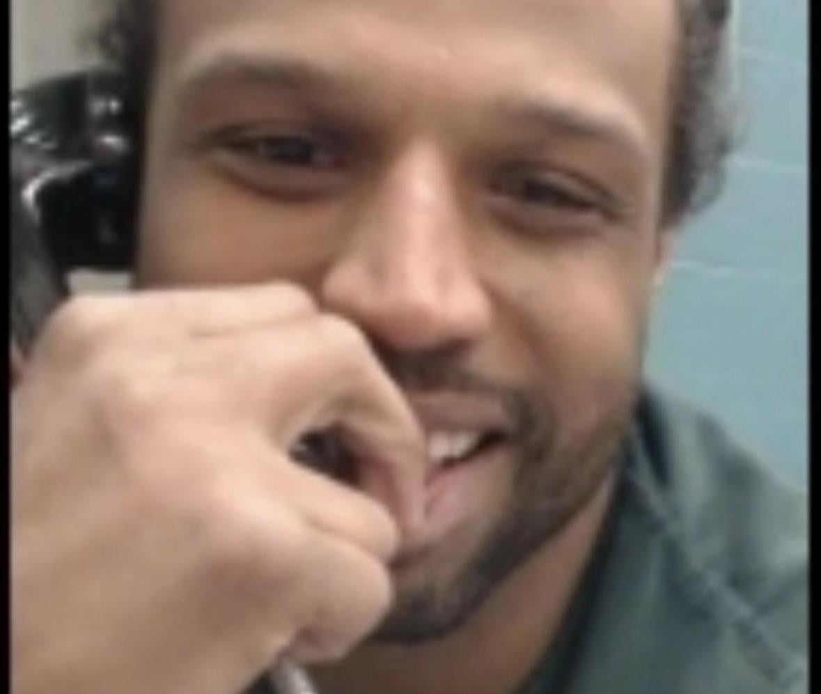 A man smiling with his hand on his mouth